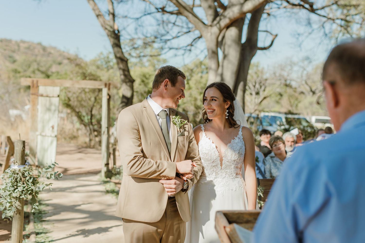 Wedding ceremony moments captured under natural tree canopy with desert mountain backdrop.
