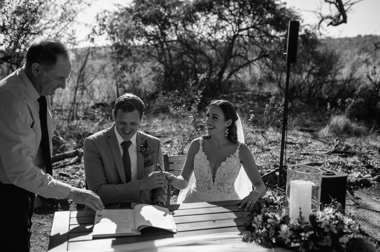 Black and white photo of wedding ceremony signing under natural desert lighting.