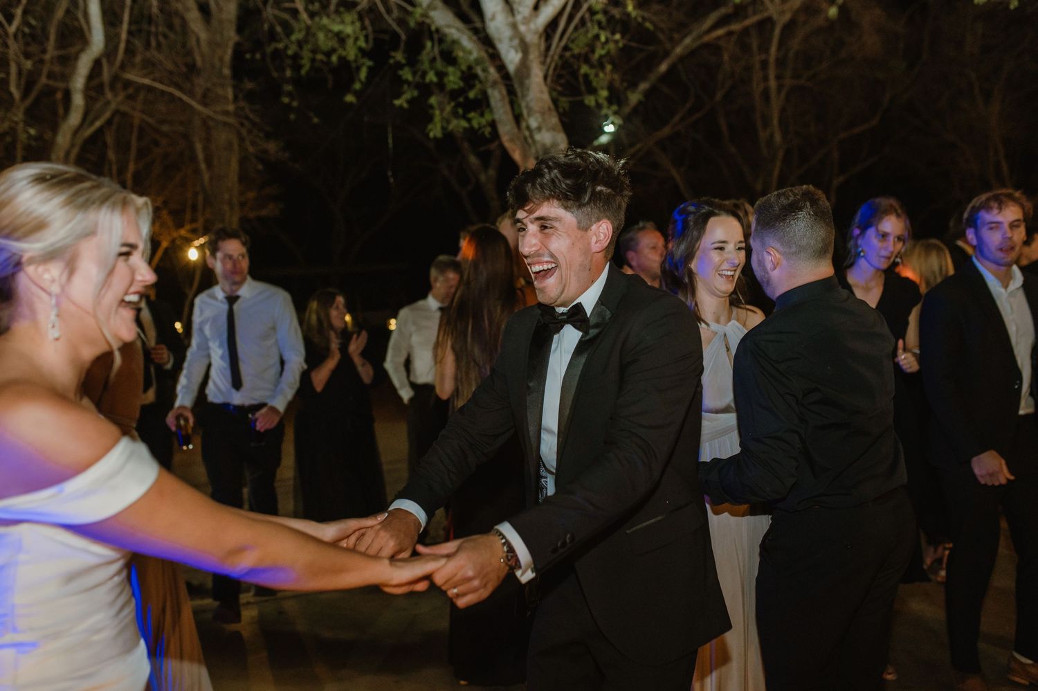 Wedding guests enjoying dance floor festivities under evening string lights.