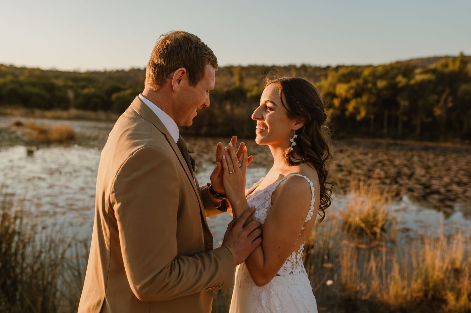 Sunset wedding portraits captured near a serene lake with warm golden lighting.