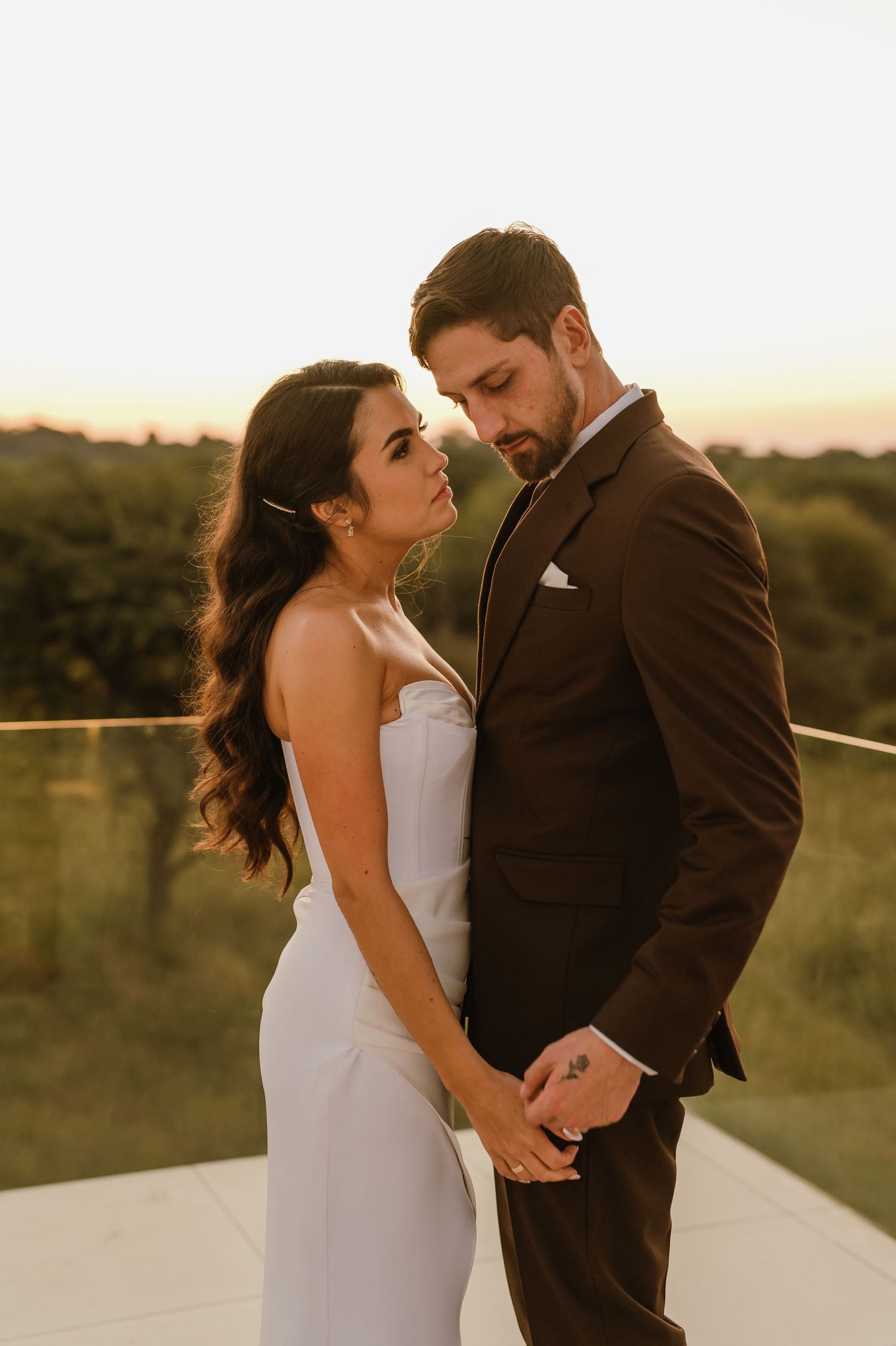 Couple in wedding attire sharing tender moments during golden hour photoshoot.