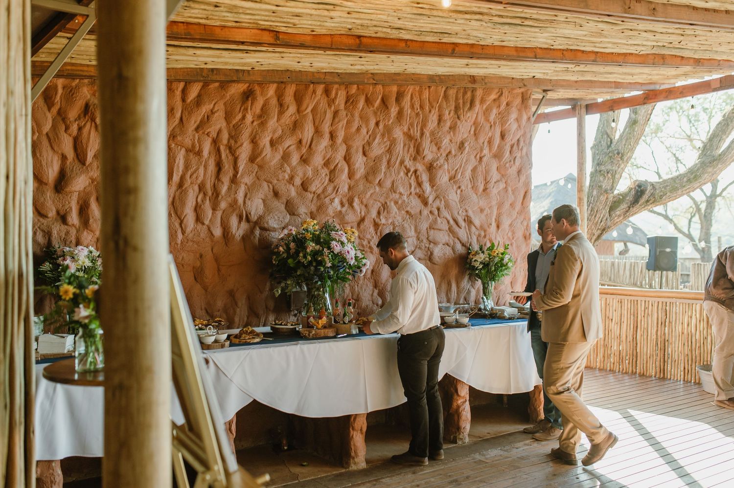 Interior view of rustic wedding venue with wooden columns and natural stone walls.