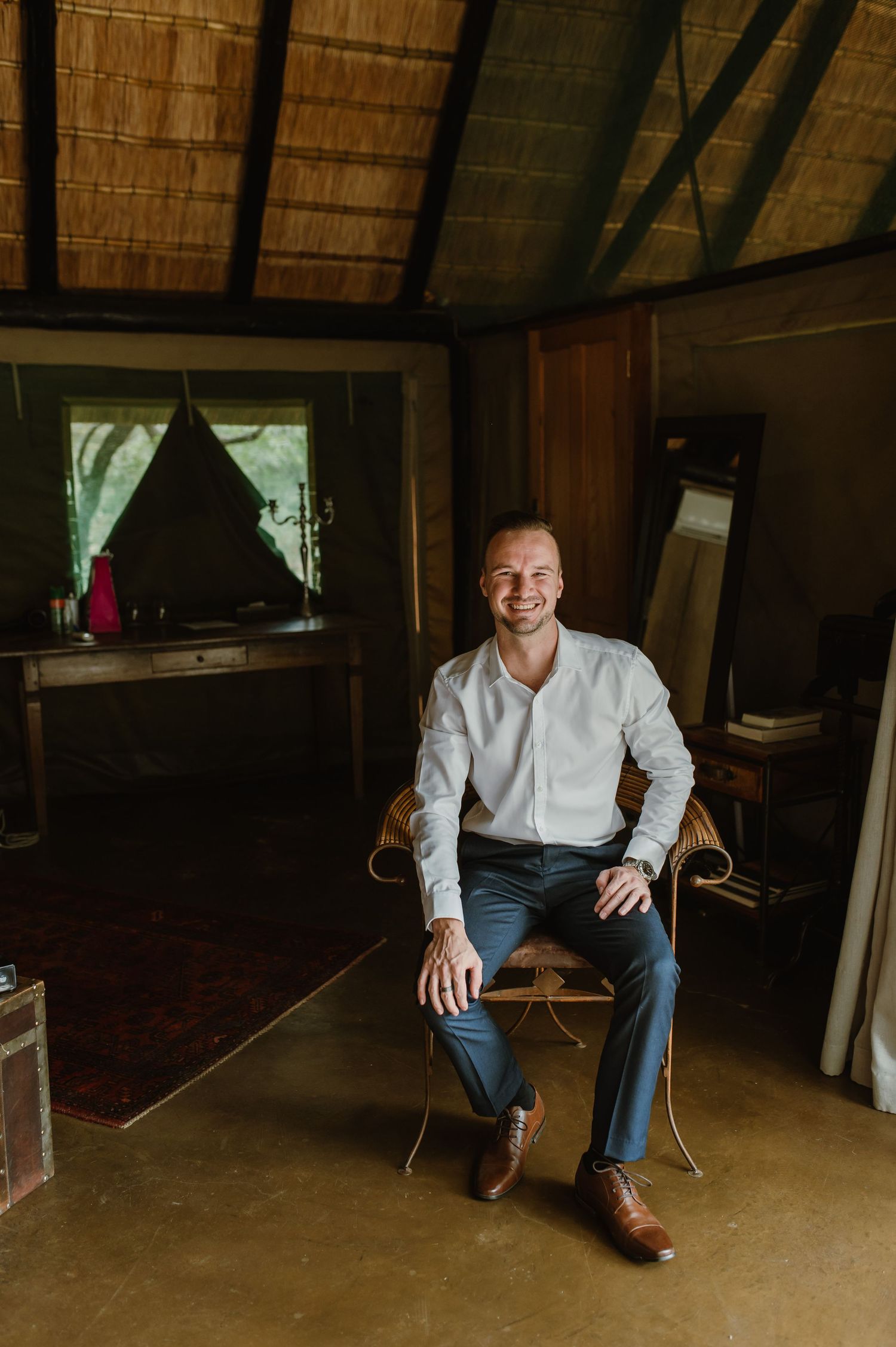 Person seated in casual attire inside rustic room with wooden ceiling beams.