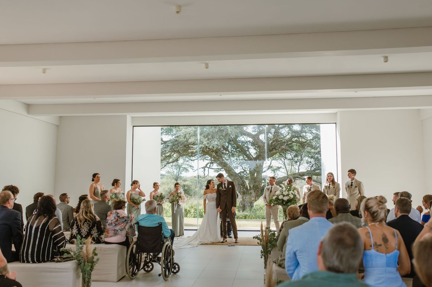 Modern wedding ceremony in bright venue with large windows and natural light.