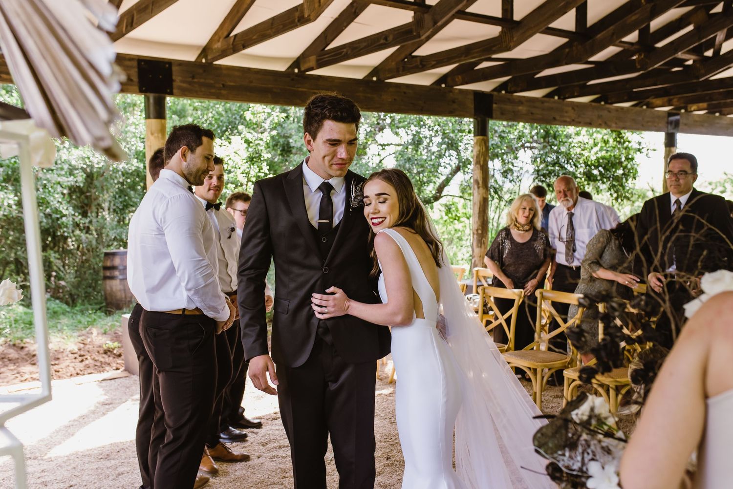Wedding ceremony moments captured under a rustic wooden pavilion with natural lighting.