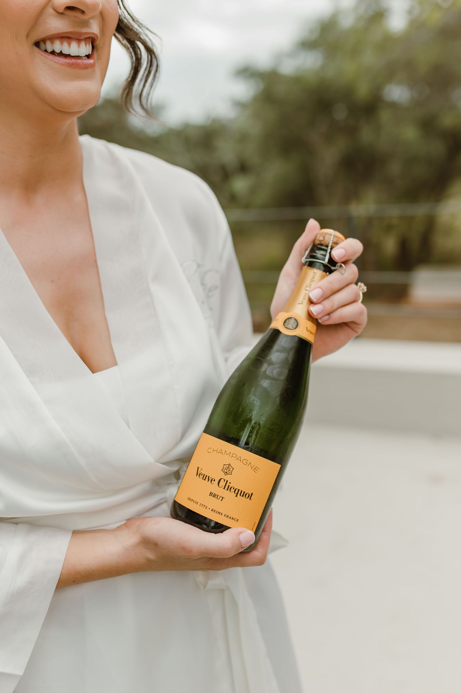 Hands holding bottles of Veuve Clicquot champagne in a celebratory wedding day sequence.