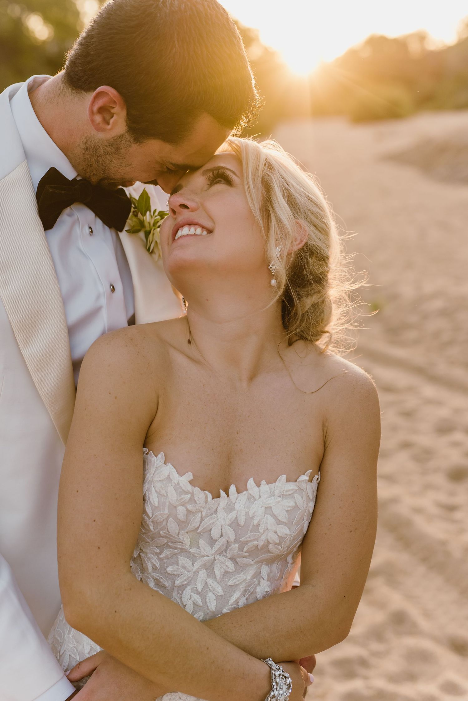 Romantic sunset beach portrait of wedding couple in elegant attire.