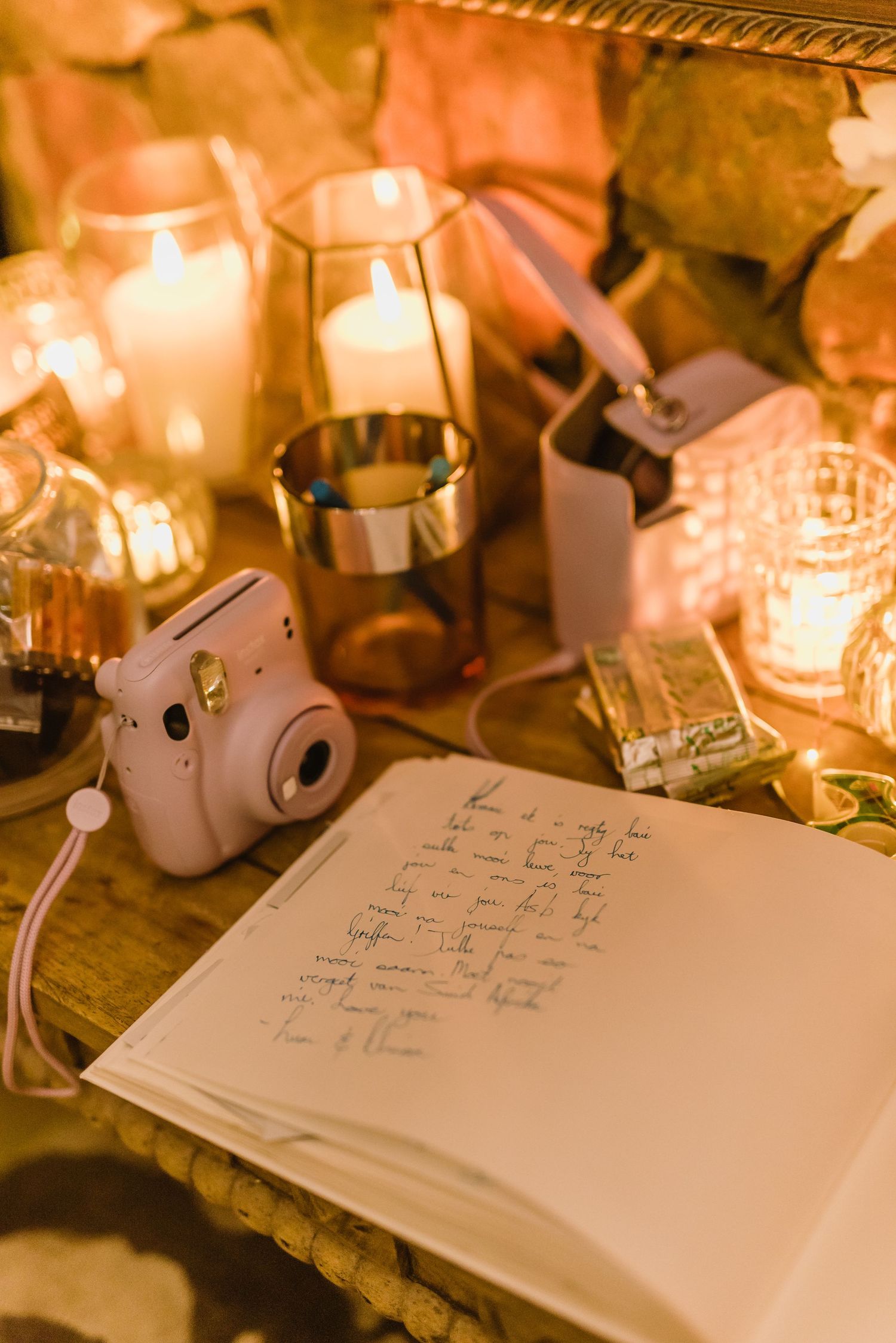Guest book and decorative candles arranged on wooden table at evening reception.