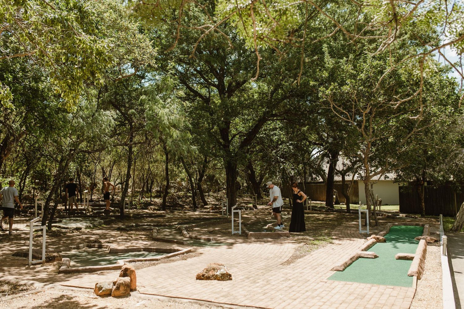 Mini golf course winding through shaded woodland area at resort.