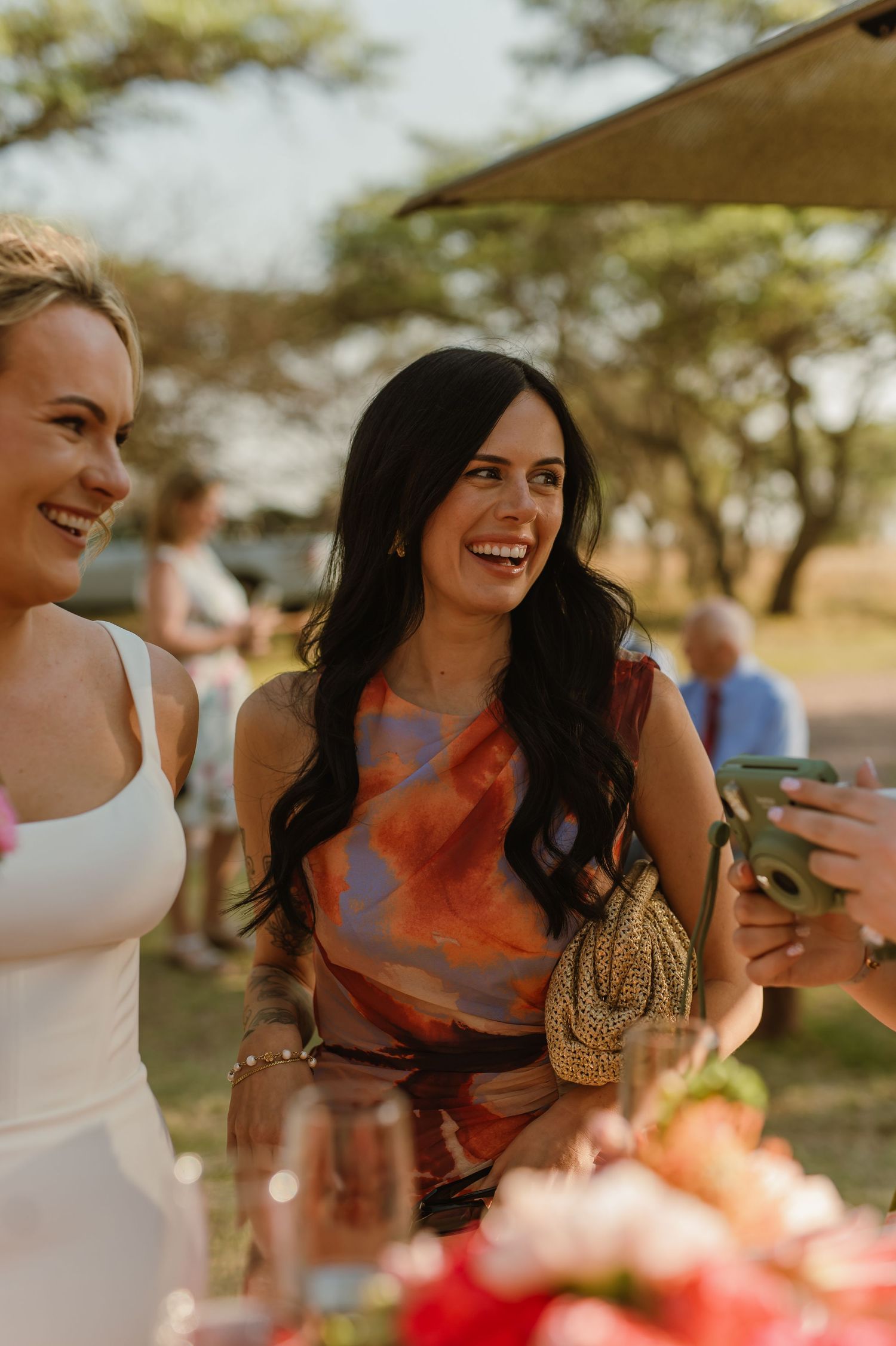 Outdoor wedding reception guests enjoying drinks and conversation in warm sunlight.