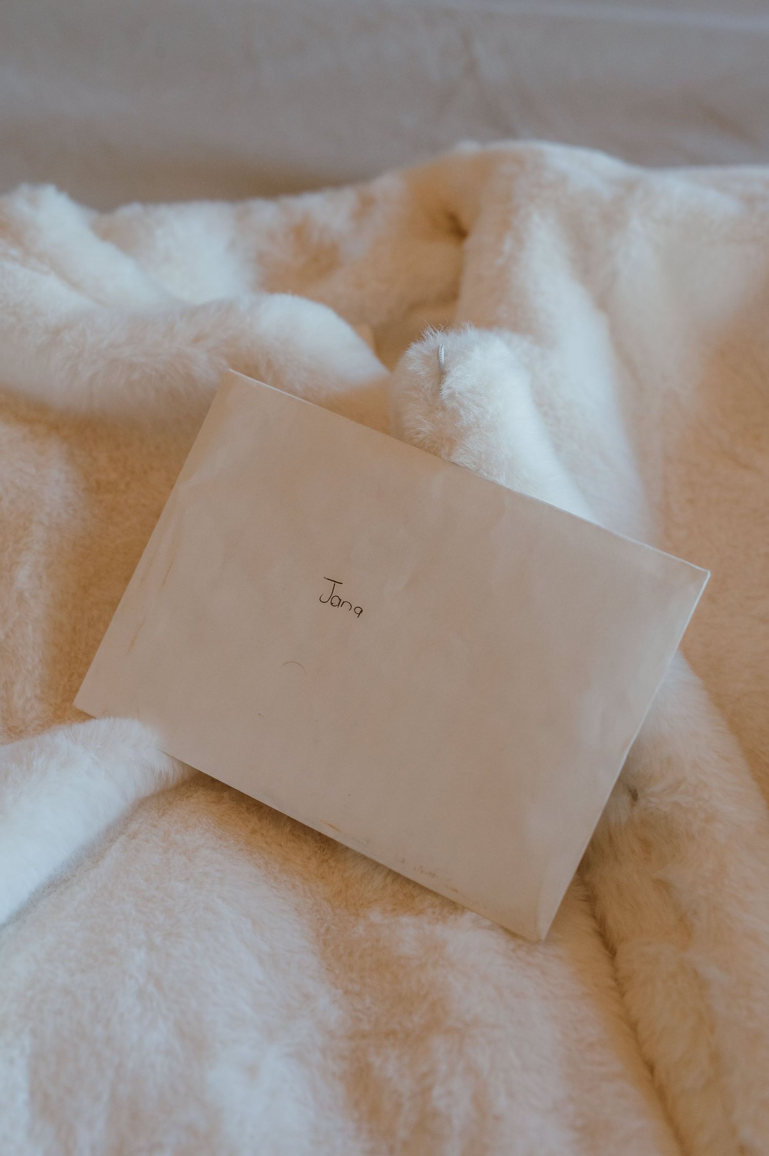 Small white paper card placed on soft white textured fabric or blanket.