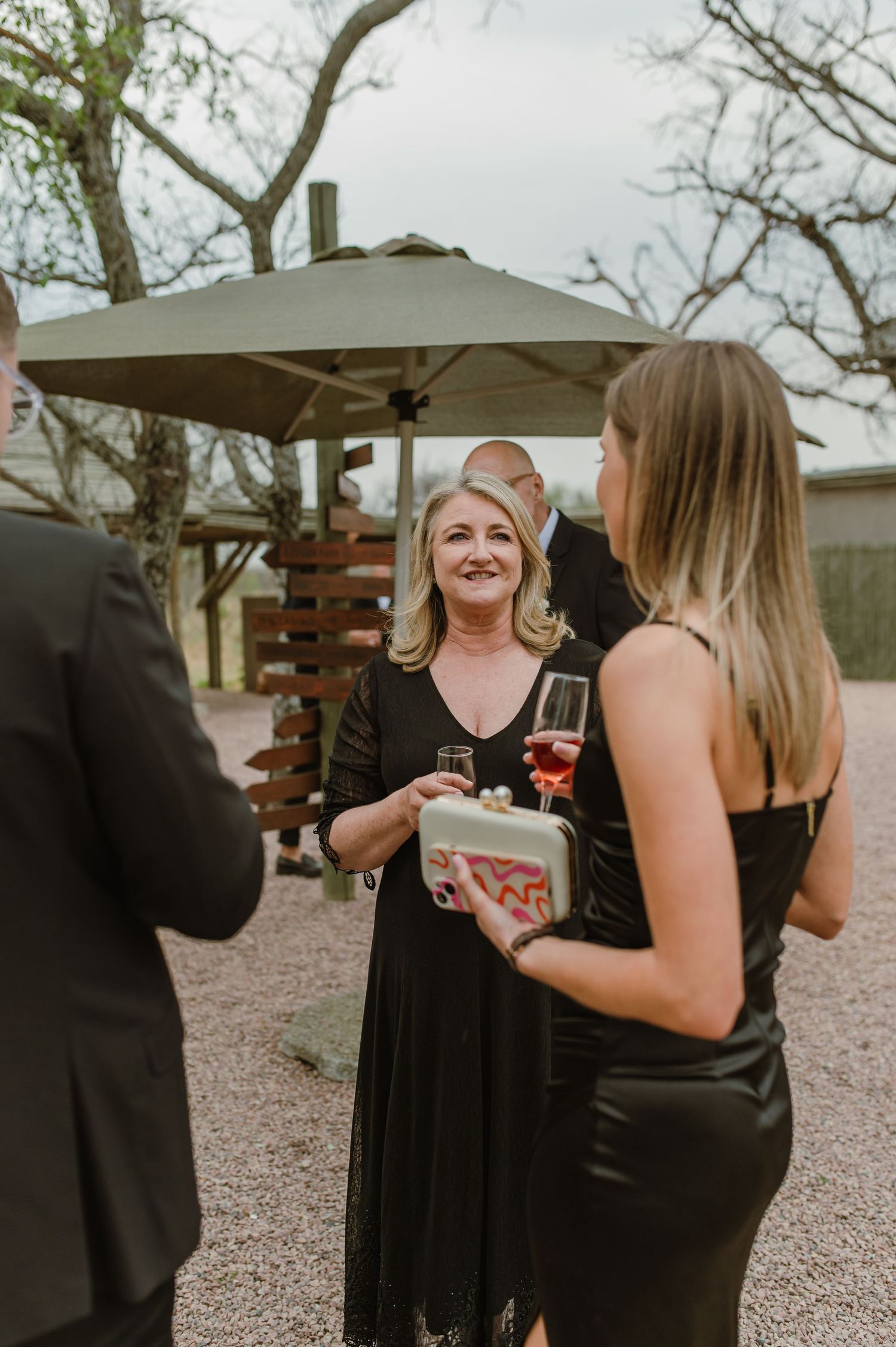 Wedding guests in formal attire mingling at outdoor reception.