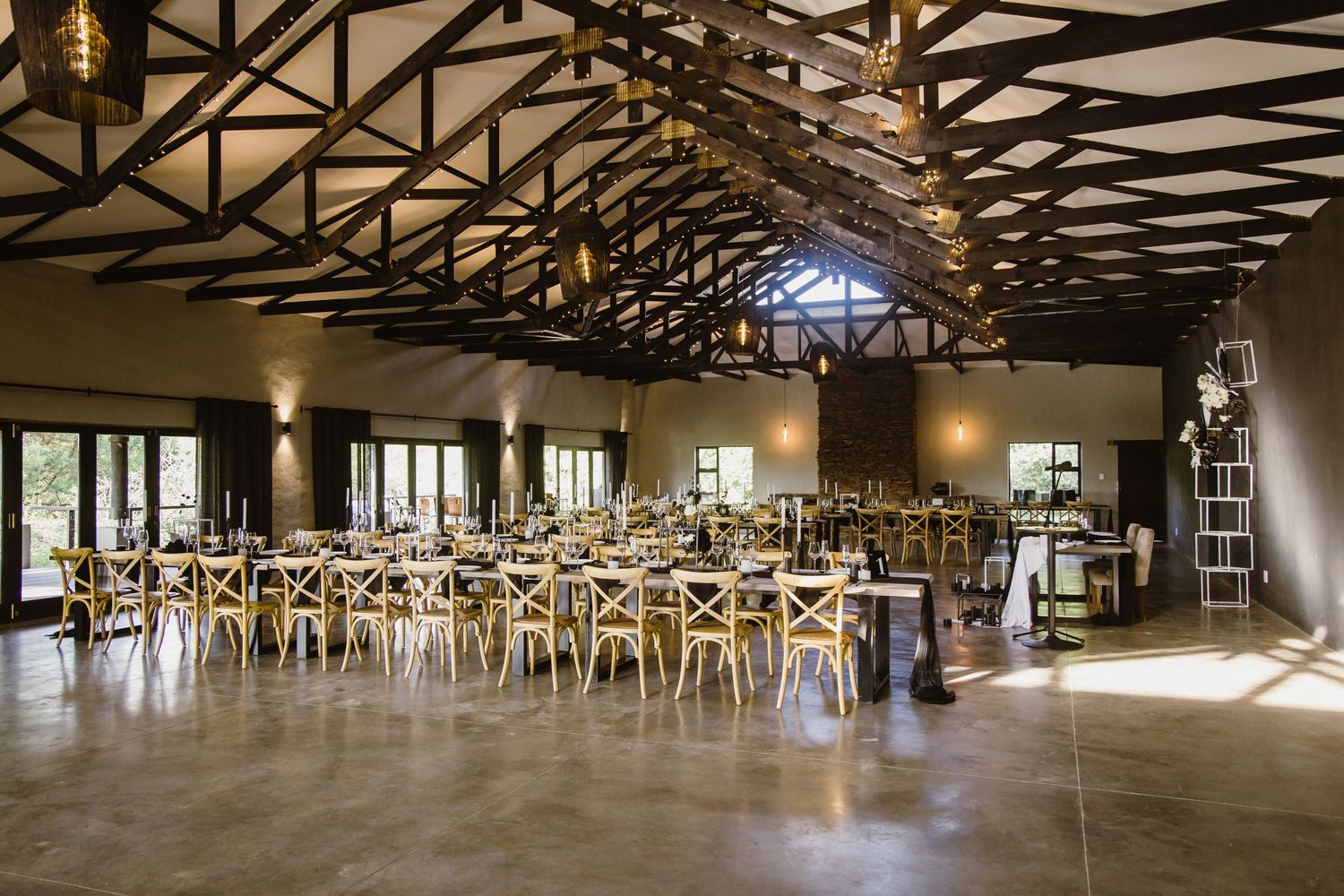 Wide angle view of an empty event venue with wooden trusses and yellow chairs.