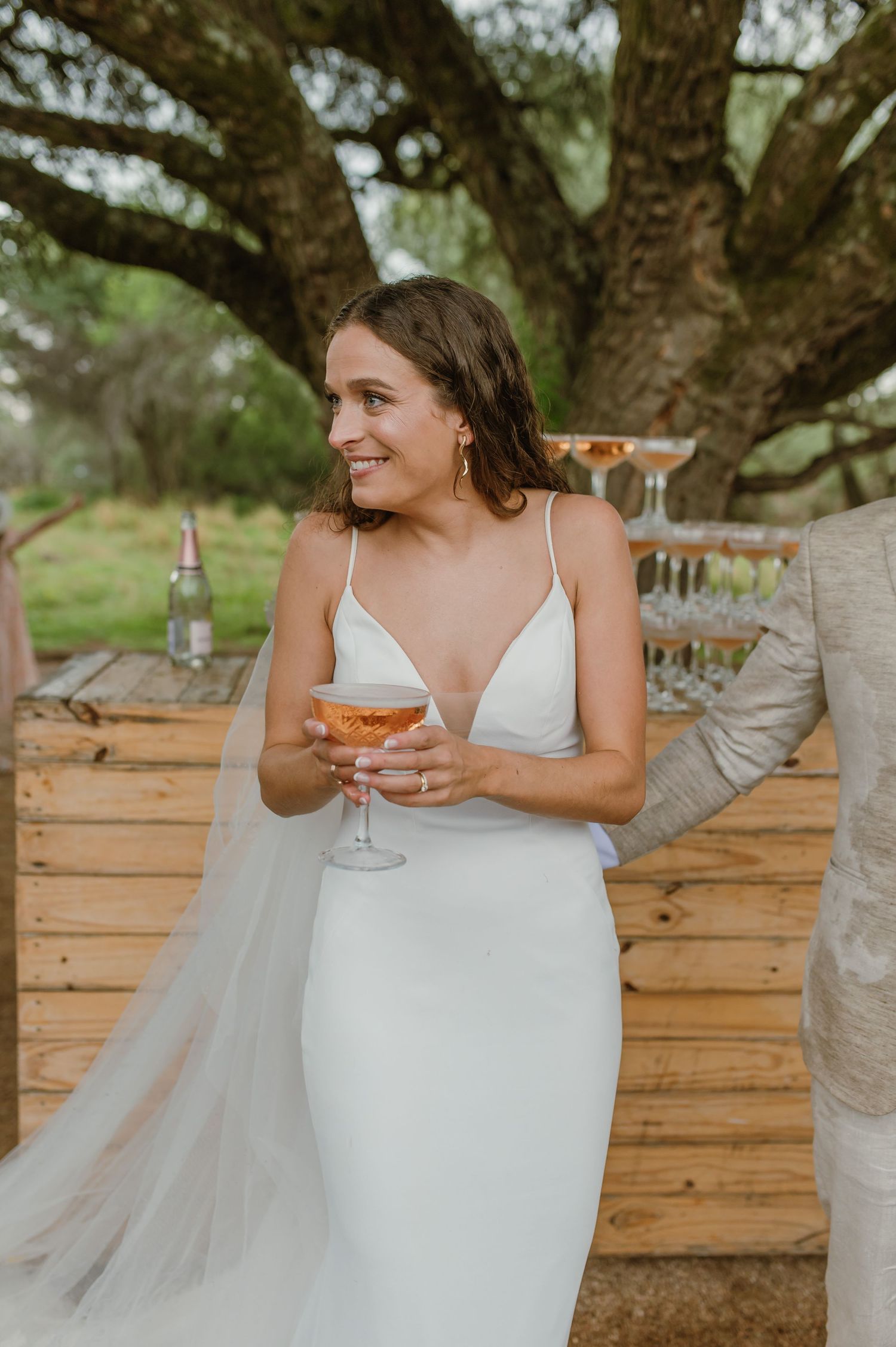 Elegant wedding scene with white dress flowing against natural outdoor setting.