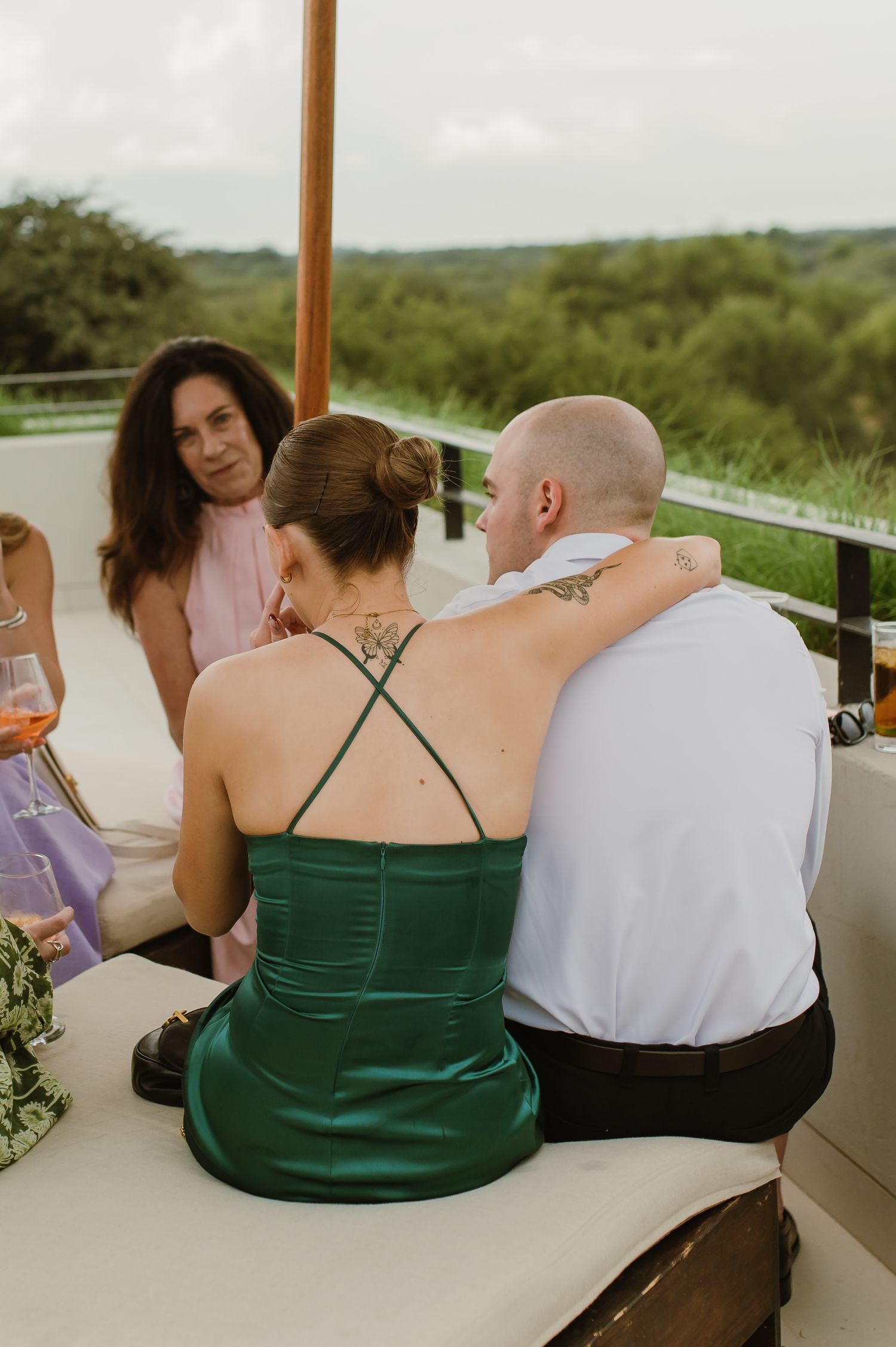 Wedding guests enjoying drinks and conversation on an outdoor patio with scenic views.