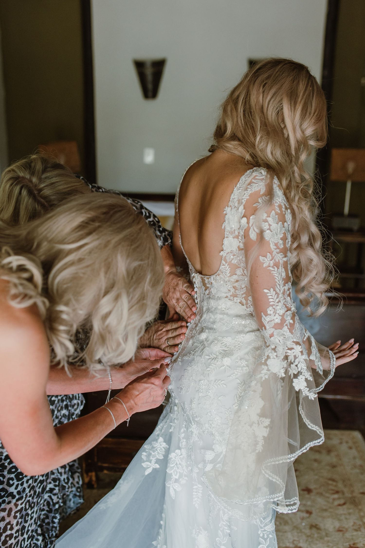 Close-up of intricate lace details on a white wedding dress being adjusted.