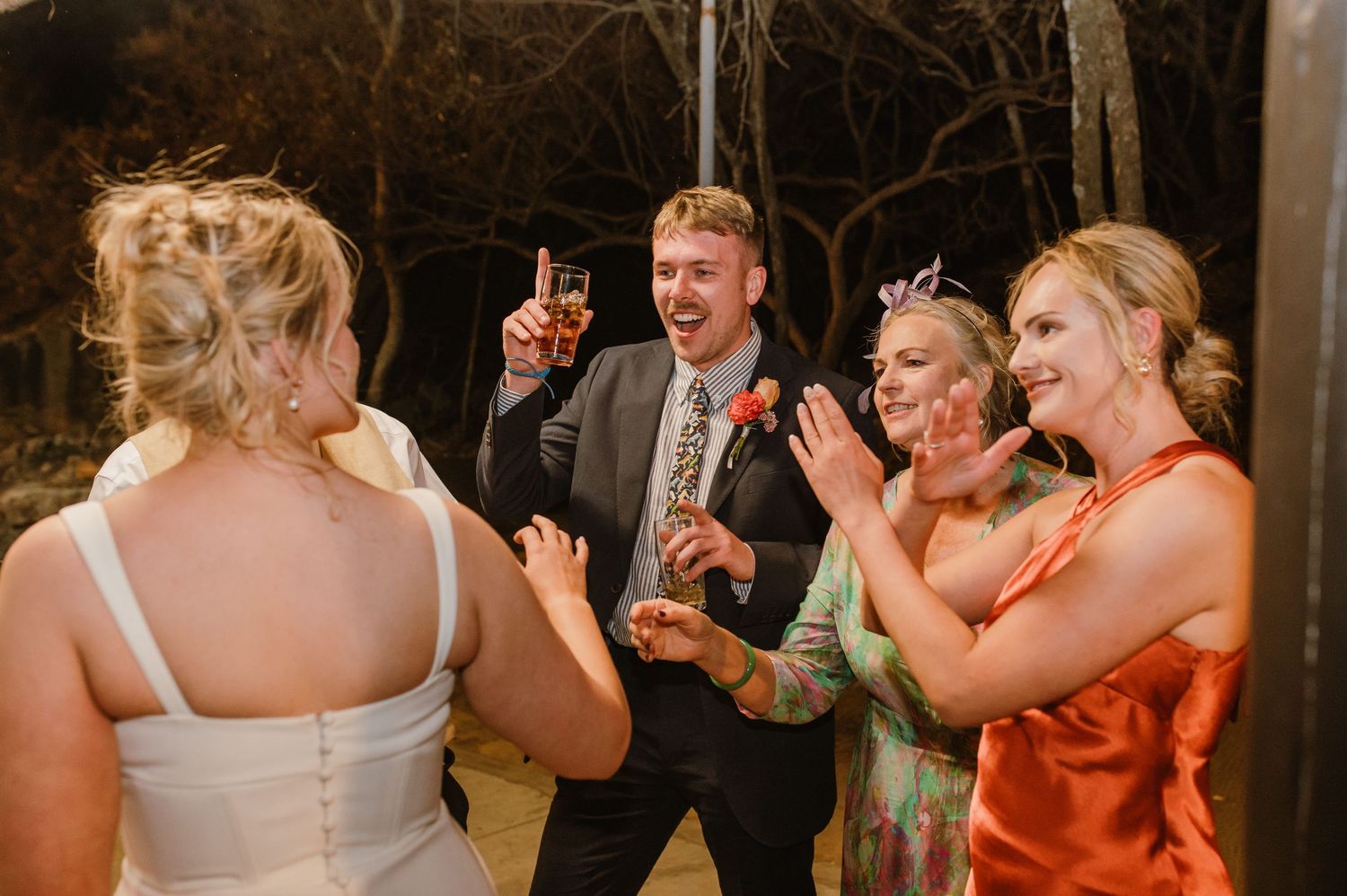 Wedding guests celebrate on the dance floor at a rustic reception venue.