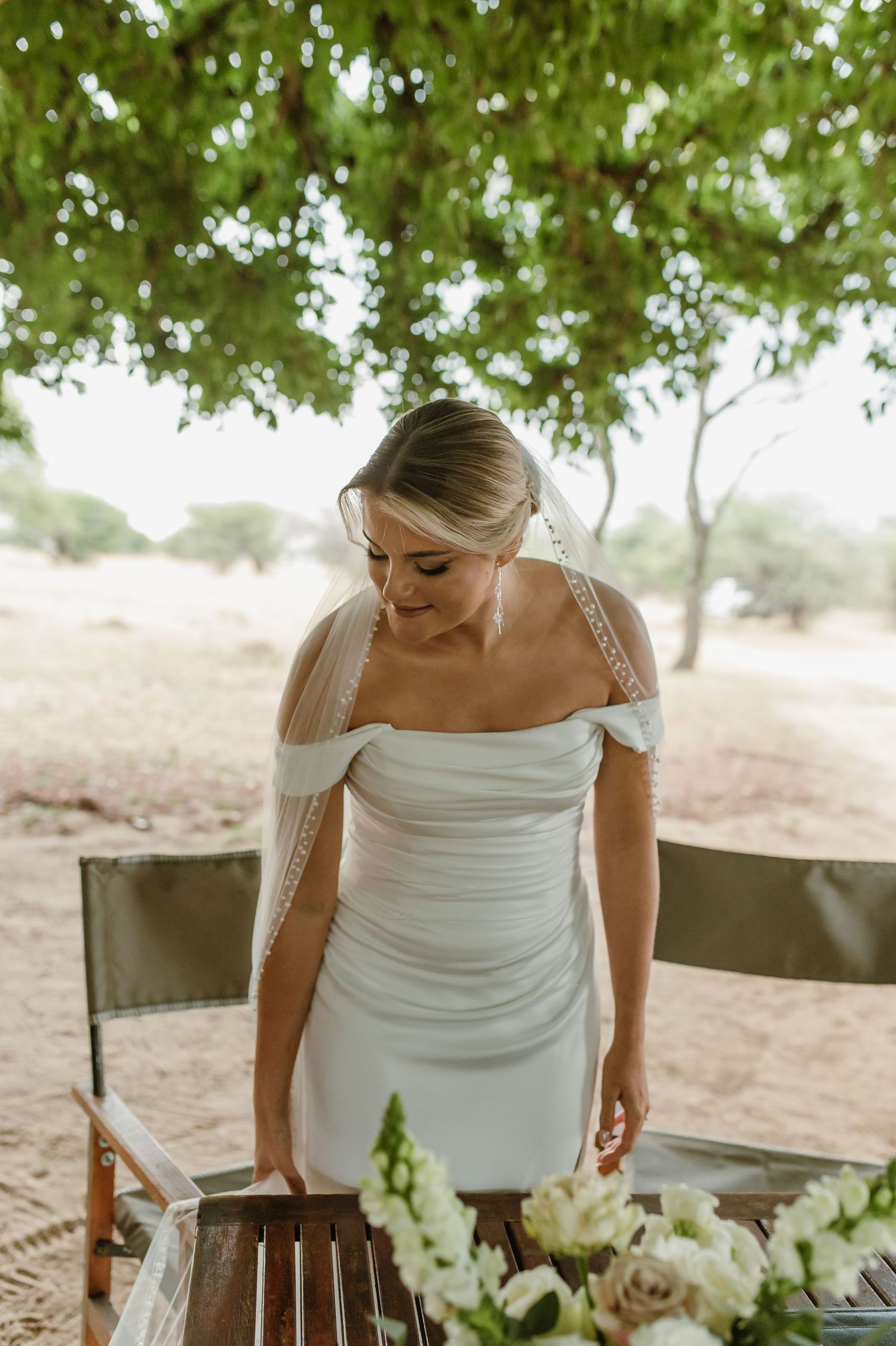 Elegant white wedding dress detail shown against natural outdoor backdrop.