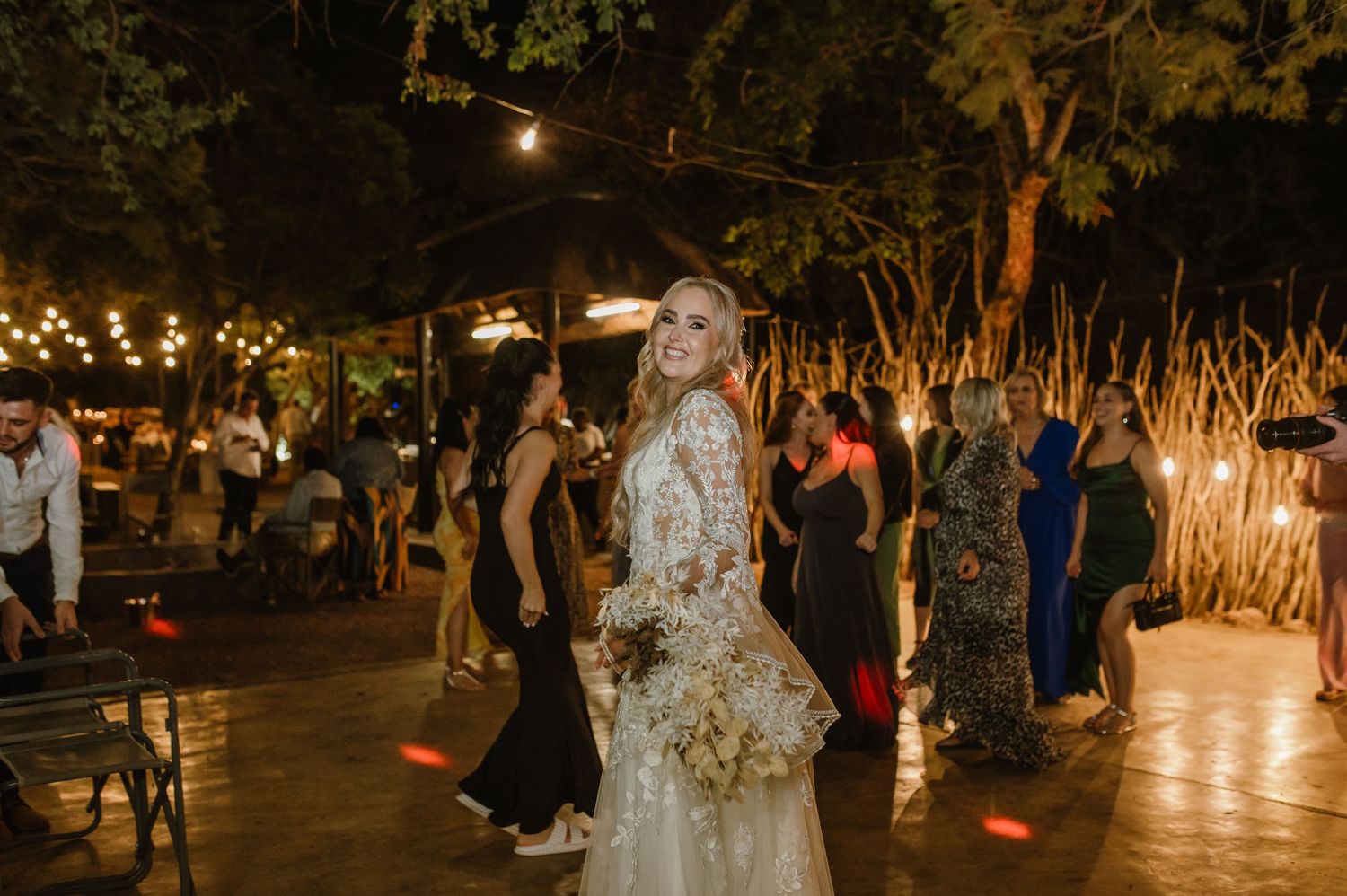 Evening wedding reception with string lights and natural decor creating a magical outdoor atmosphere.