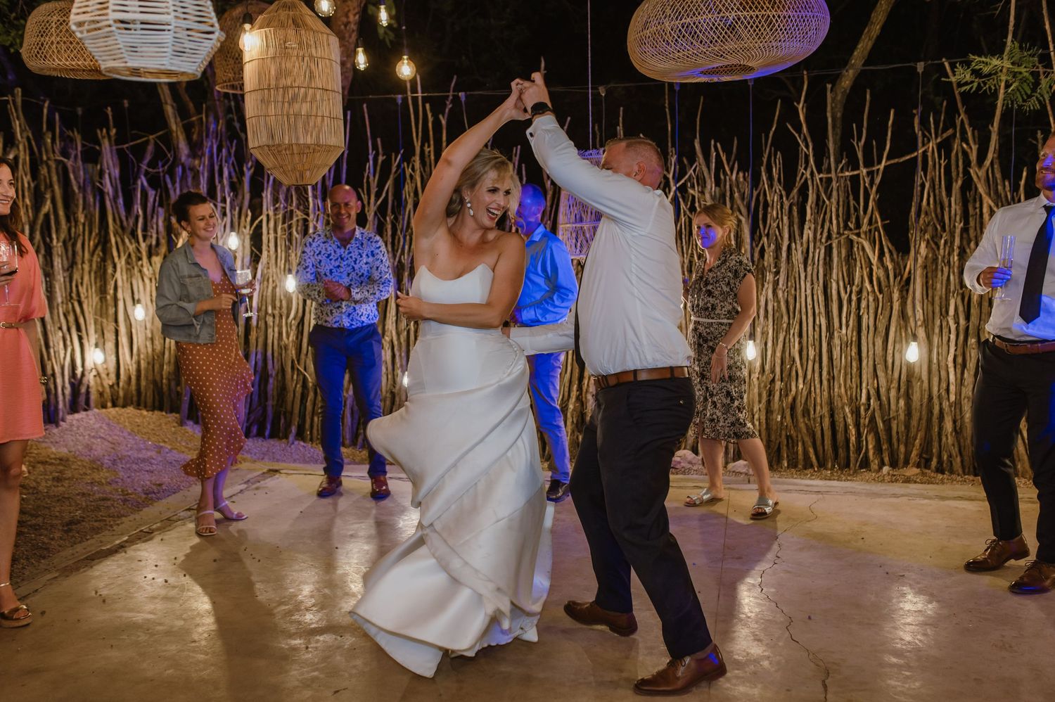 Wedding celebration in a rustic bamboo-decorated venue with hanging lantern lights.
