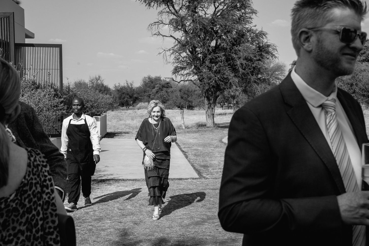 Wedding guests socializing outdoors in formal attire.