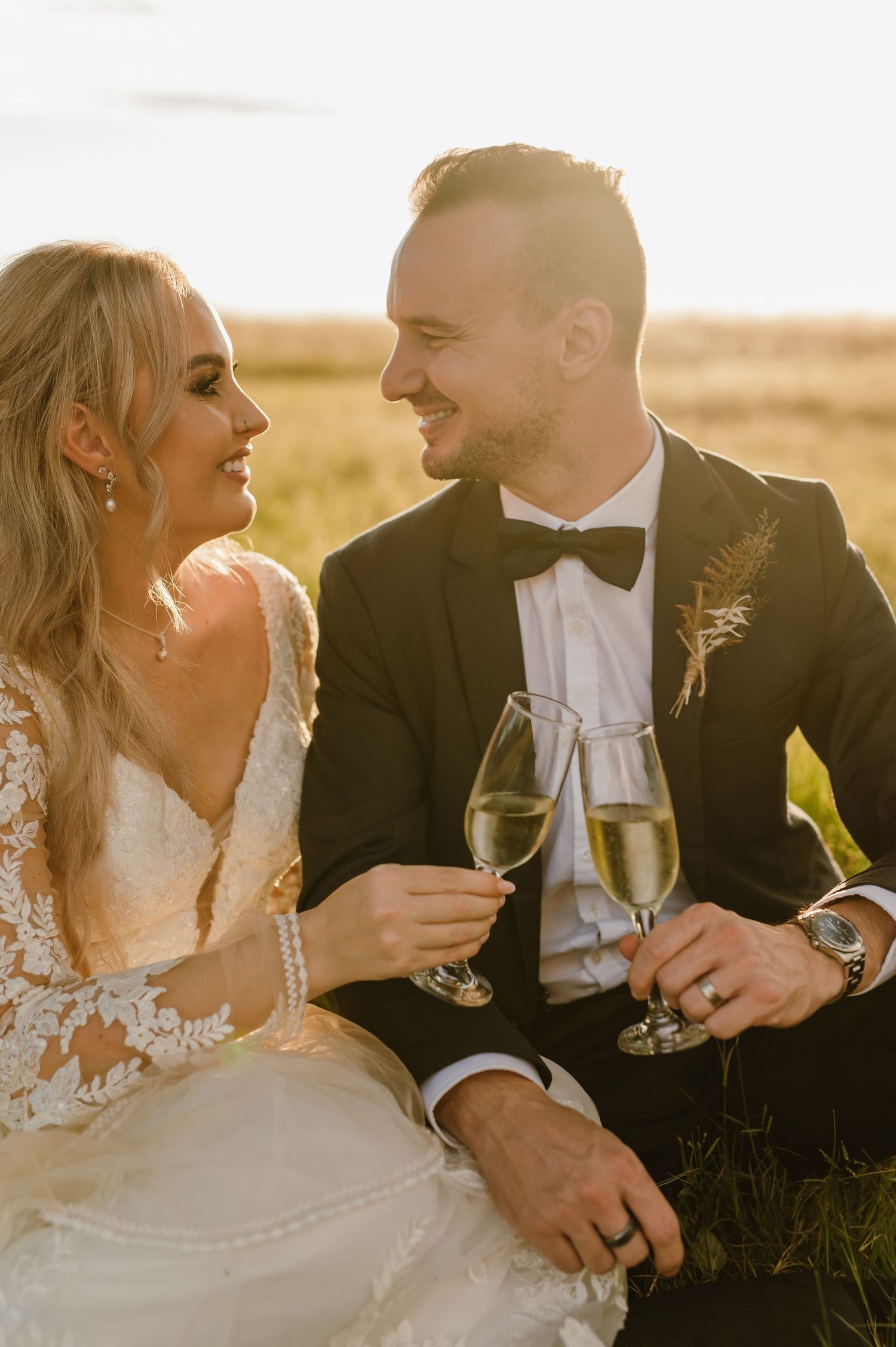 A couple shares champagne and laughter during their sunset wedding photoshoot.