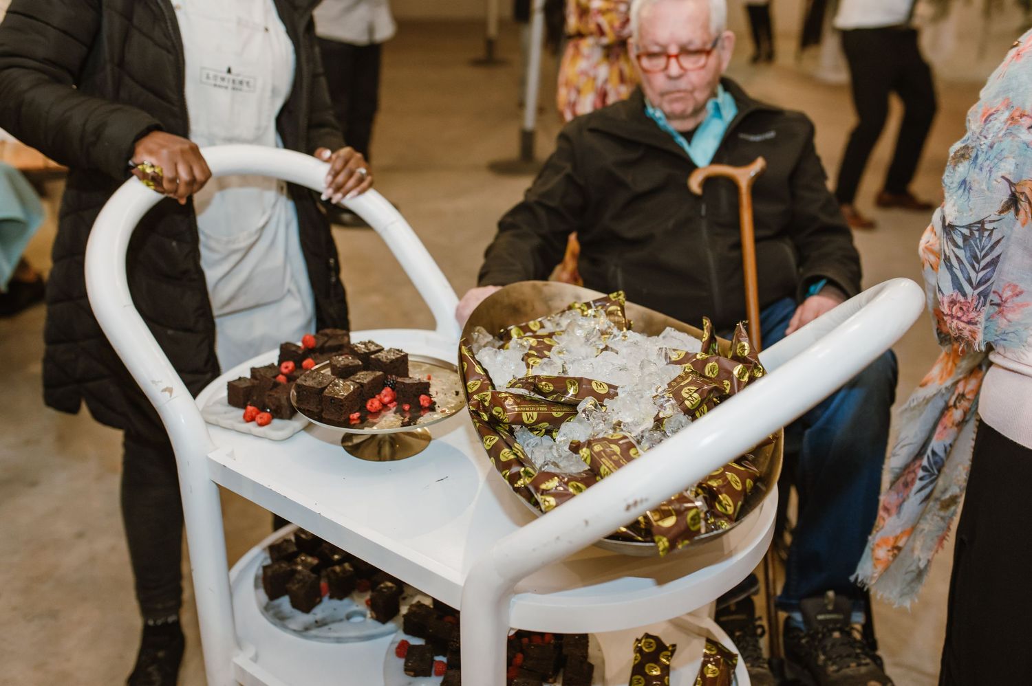 White serving cart filled with assorted desserts and treats at an event.