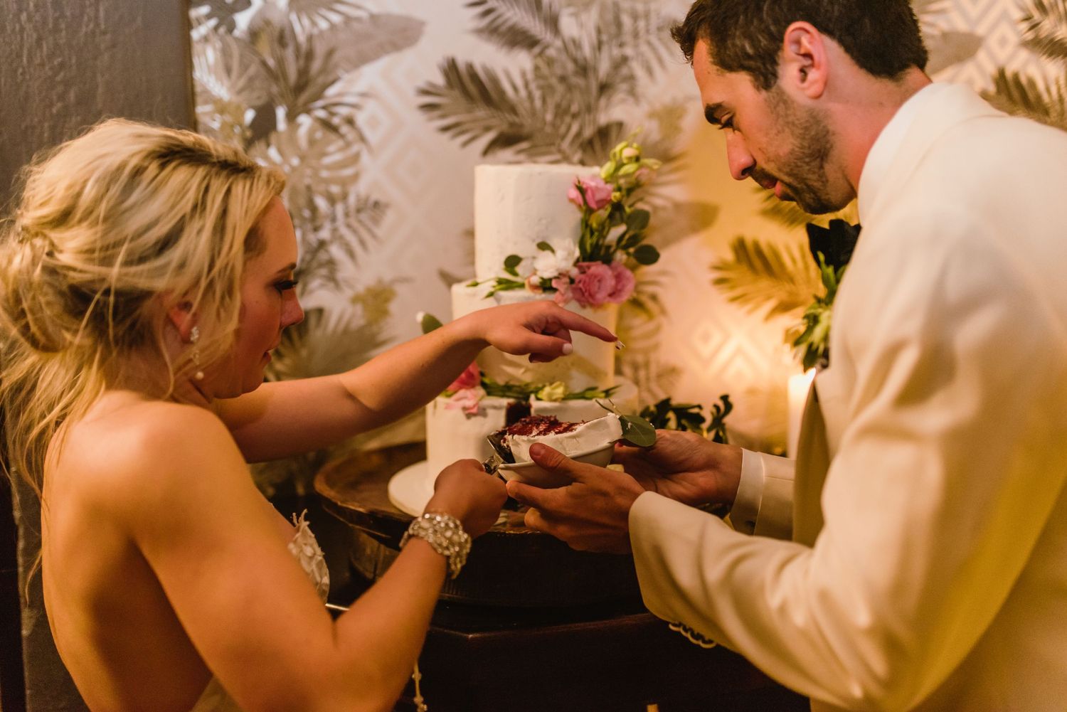 Intimate cake cutting ceremony at wedding reception with romantic ambient lighting.