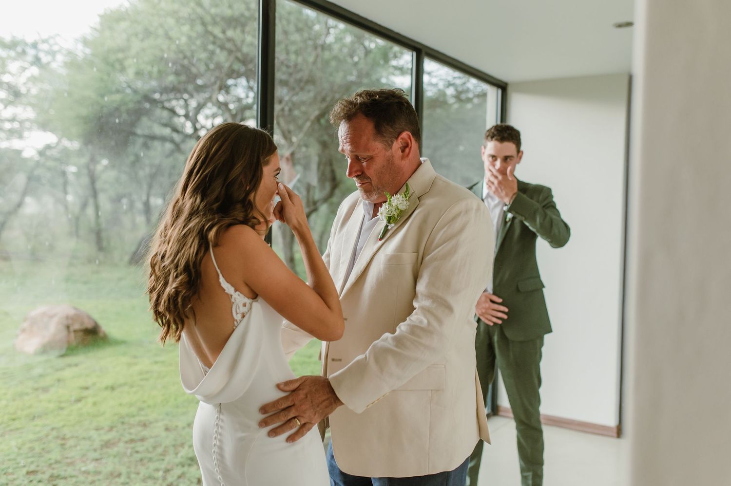 Candid wedding moments captured through large windows with natural lighting.