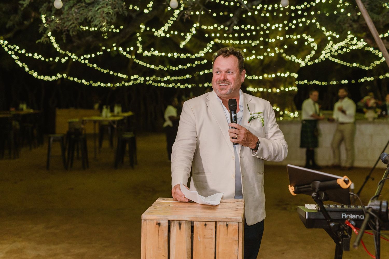 String lights create a magical canopy above wedding reception tables decorated with floral arrangements.