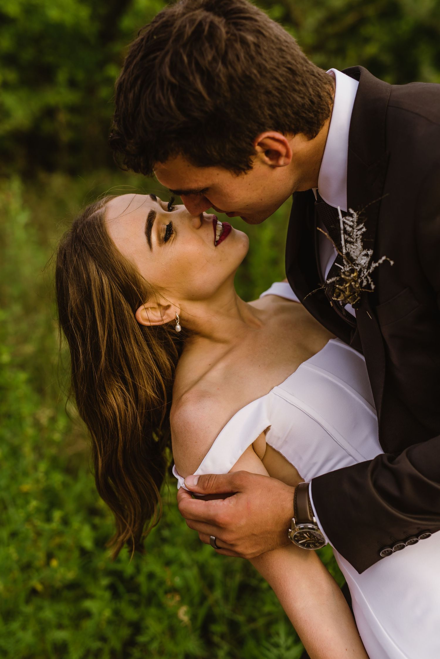 Intimate wedding portrait with couple sharing romantic kiss outdoors.