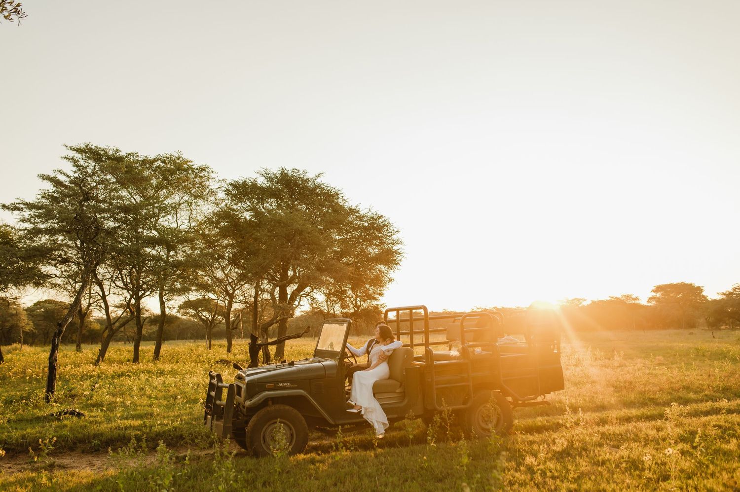 A safari vehicle silhouetted against a dramatic African sunset.