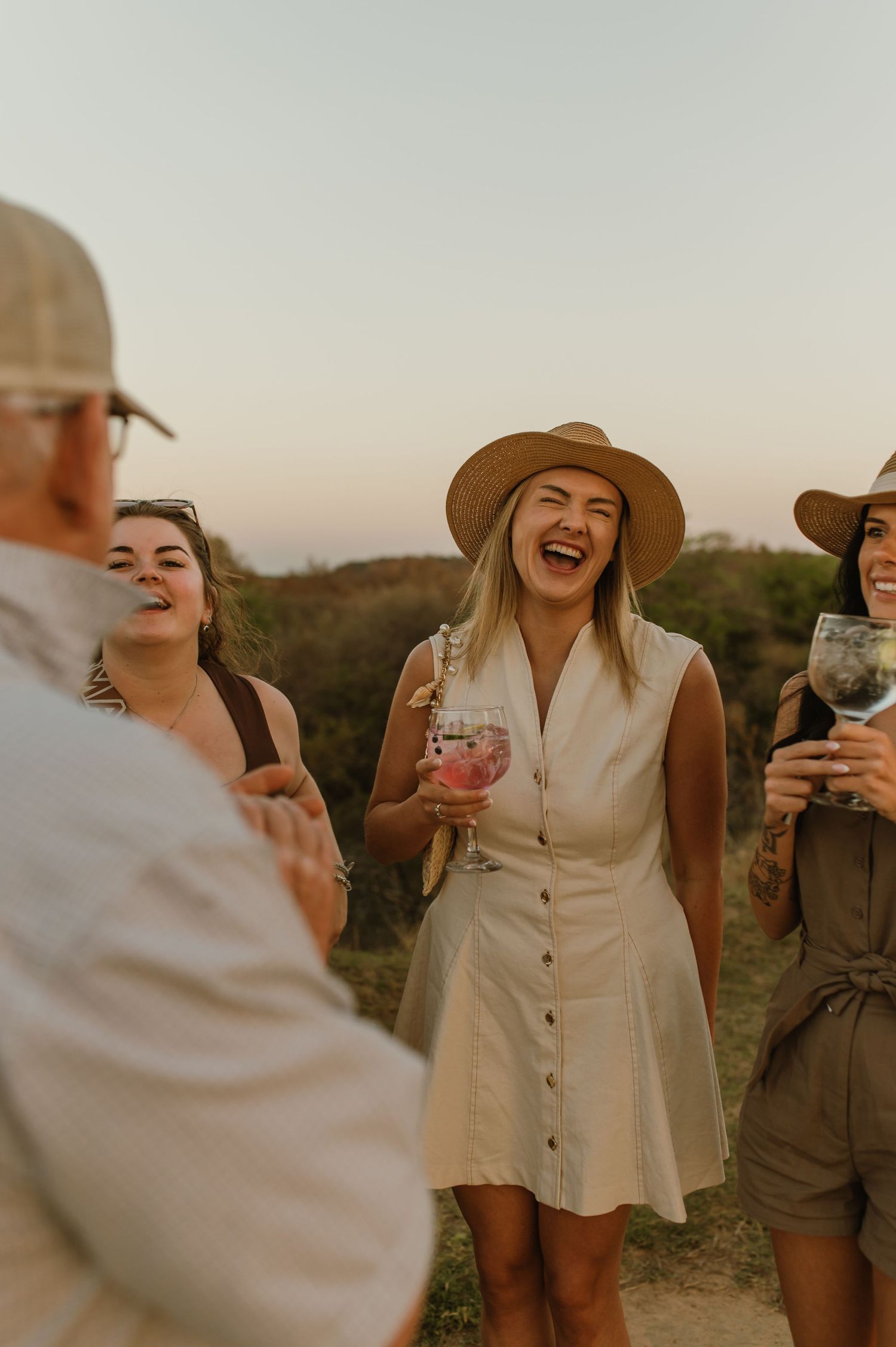 Guests laughing and socializing during sunset safari sundowner event.