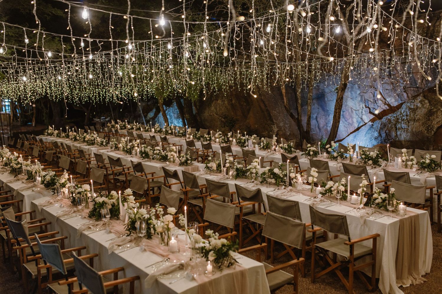 Overhead view of formal dinner tables arranged with elegant place settings under string lights.