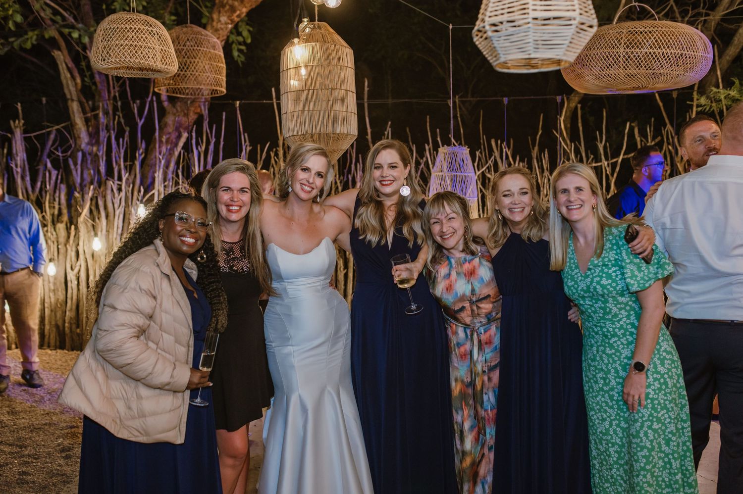 Wedding celebration with guests dancing under ambient lighting and decorative wicker lanterns.