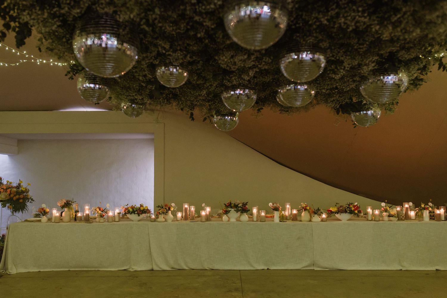 Wedding reception ceiling decorated with string lights and disco balls creating a magical atmosphere.
