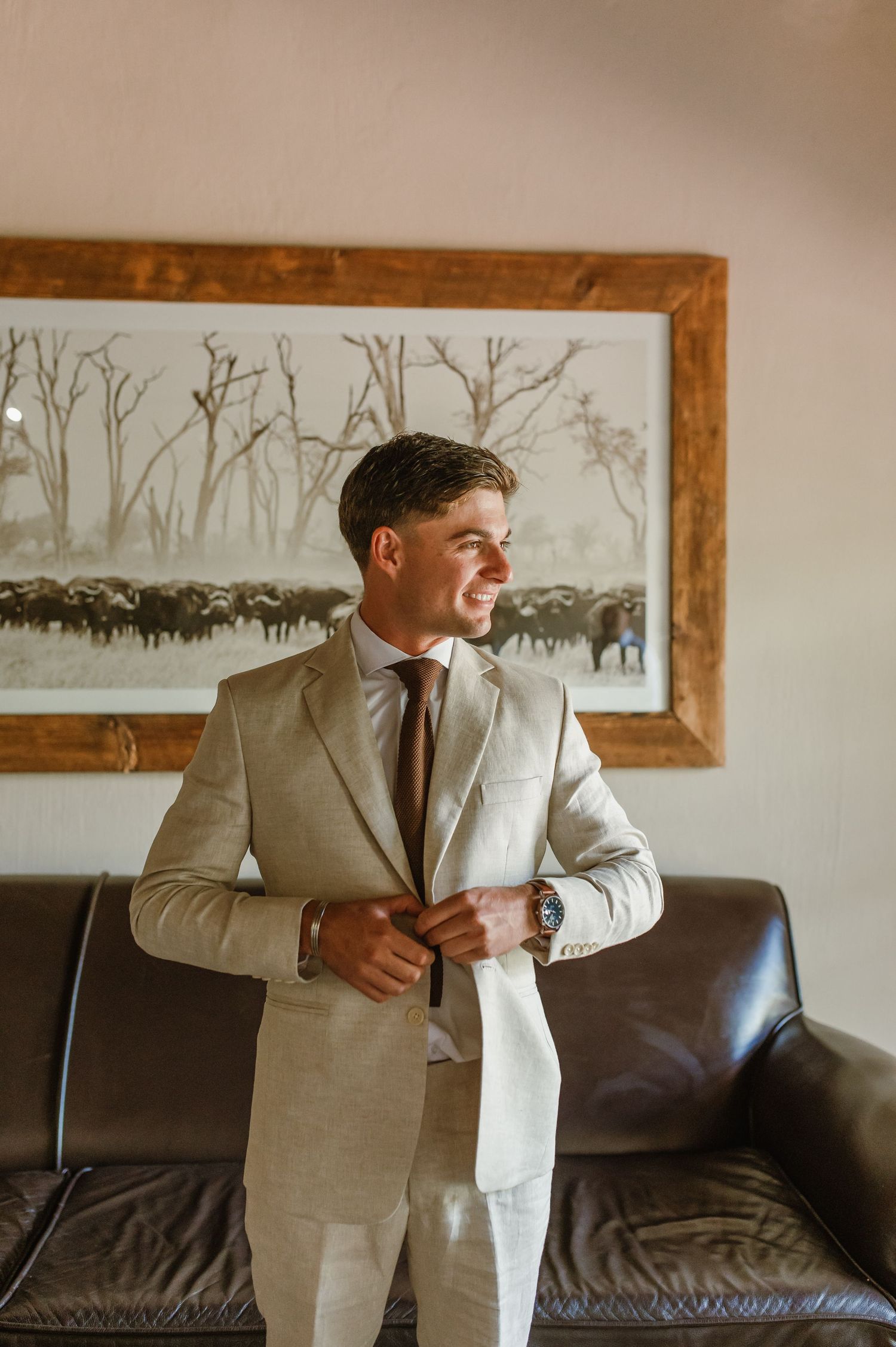 Someone in a light colored suit making final adjustments to their formal attire.