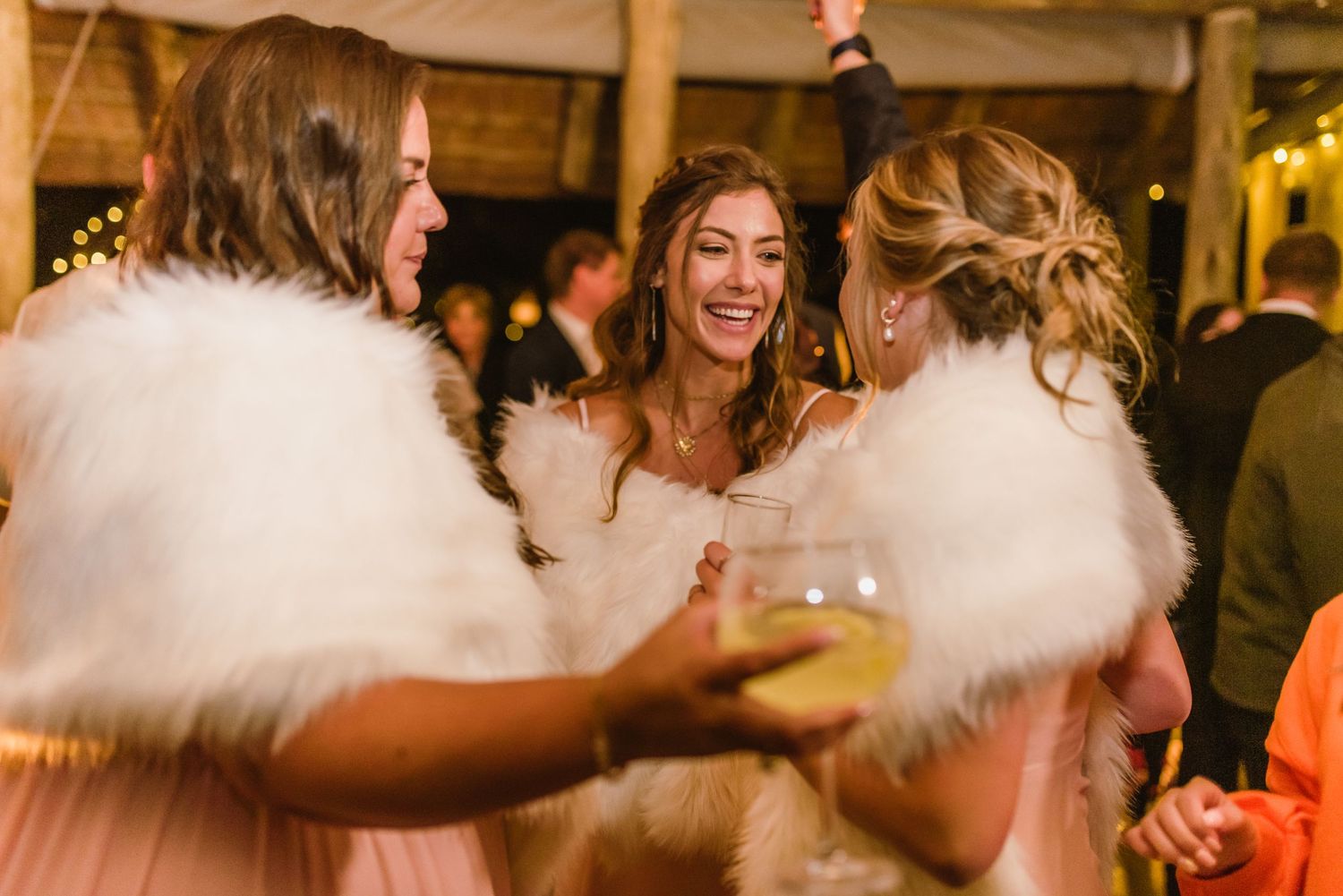 Wedding party dancing and celebrating in an elegantly decorated indoor venue with warm lighting.