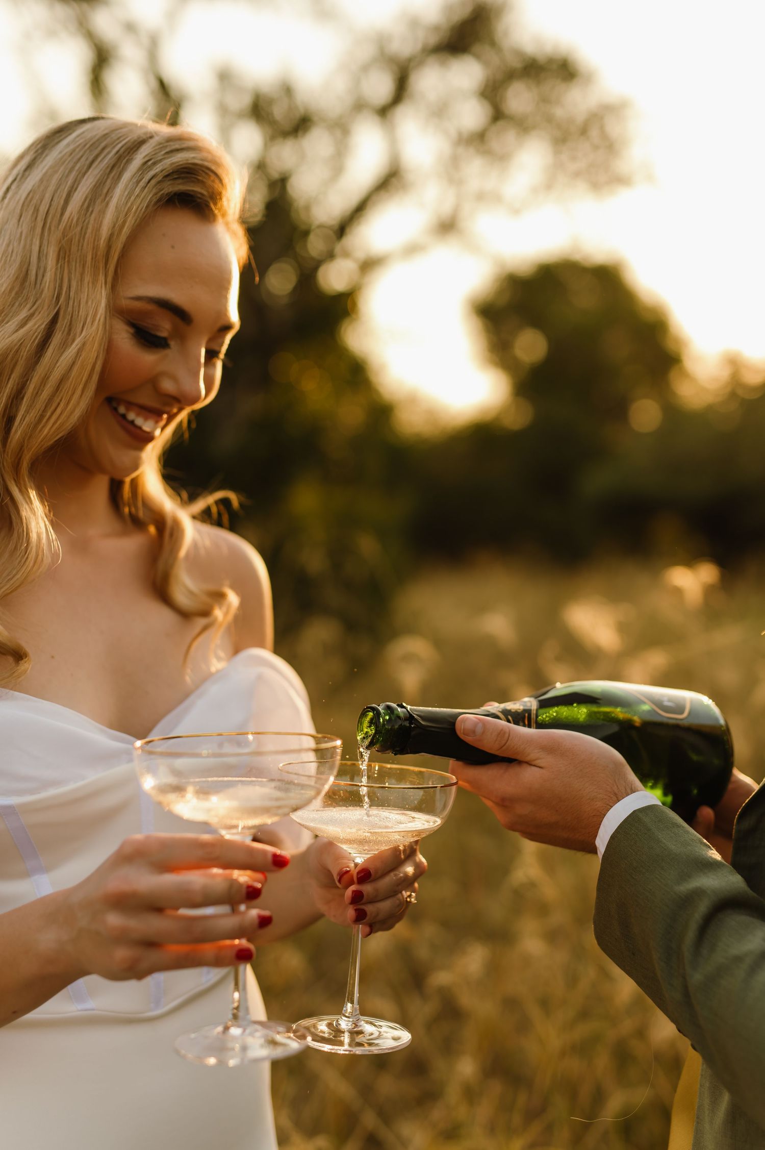 Couple toasting with champagne glasses during golden hour at their wedding.
