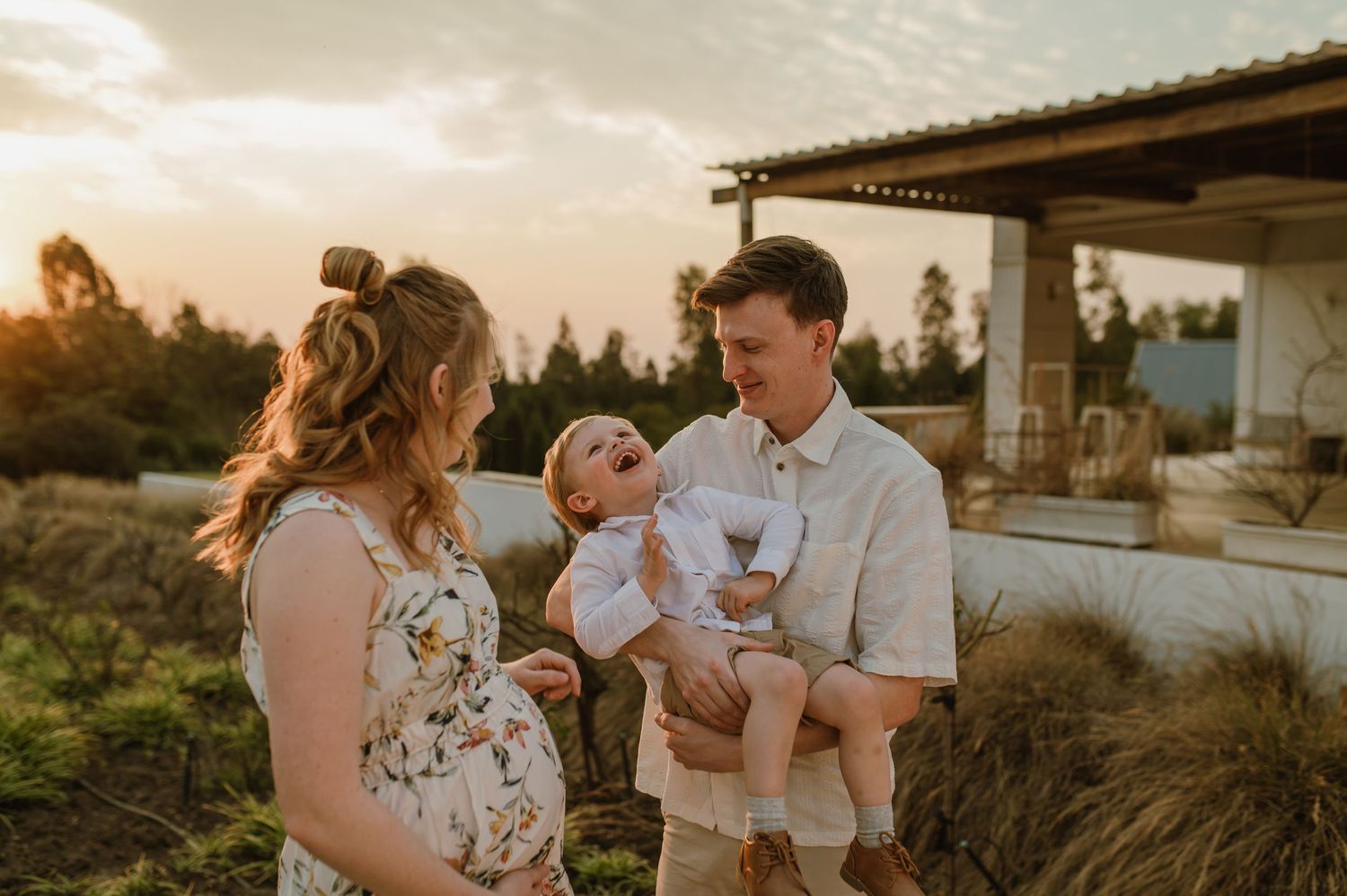 A couple shares tender moments during a golden hour photo session in a rustic outdoor setting.