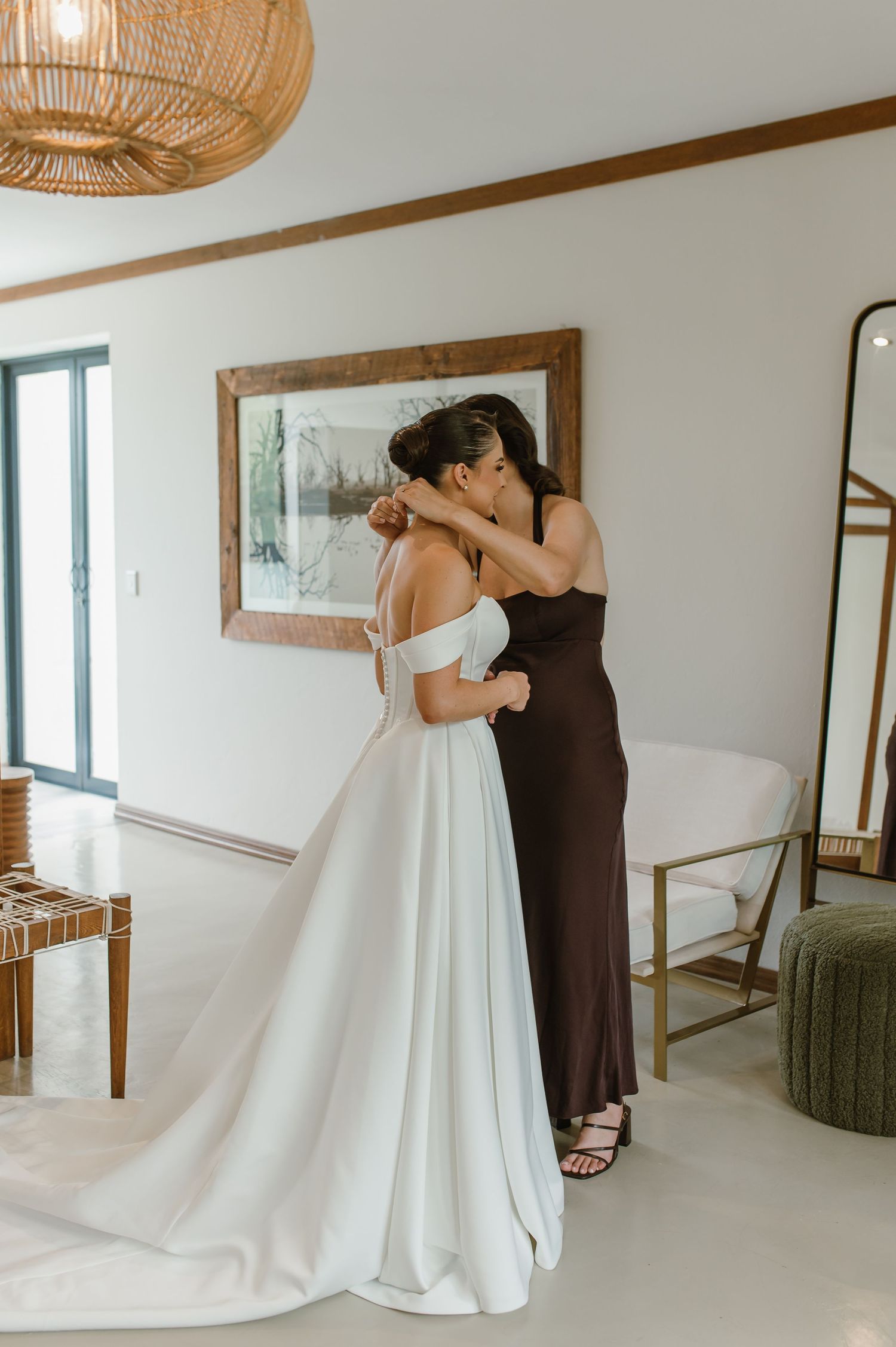 Interior wedding preparation scene with flowing white dress and rattan pendant lighting.