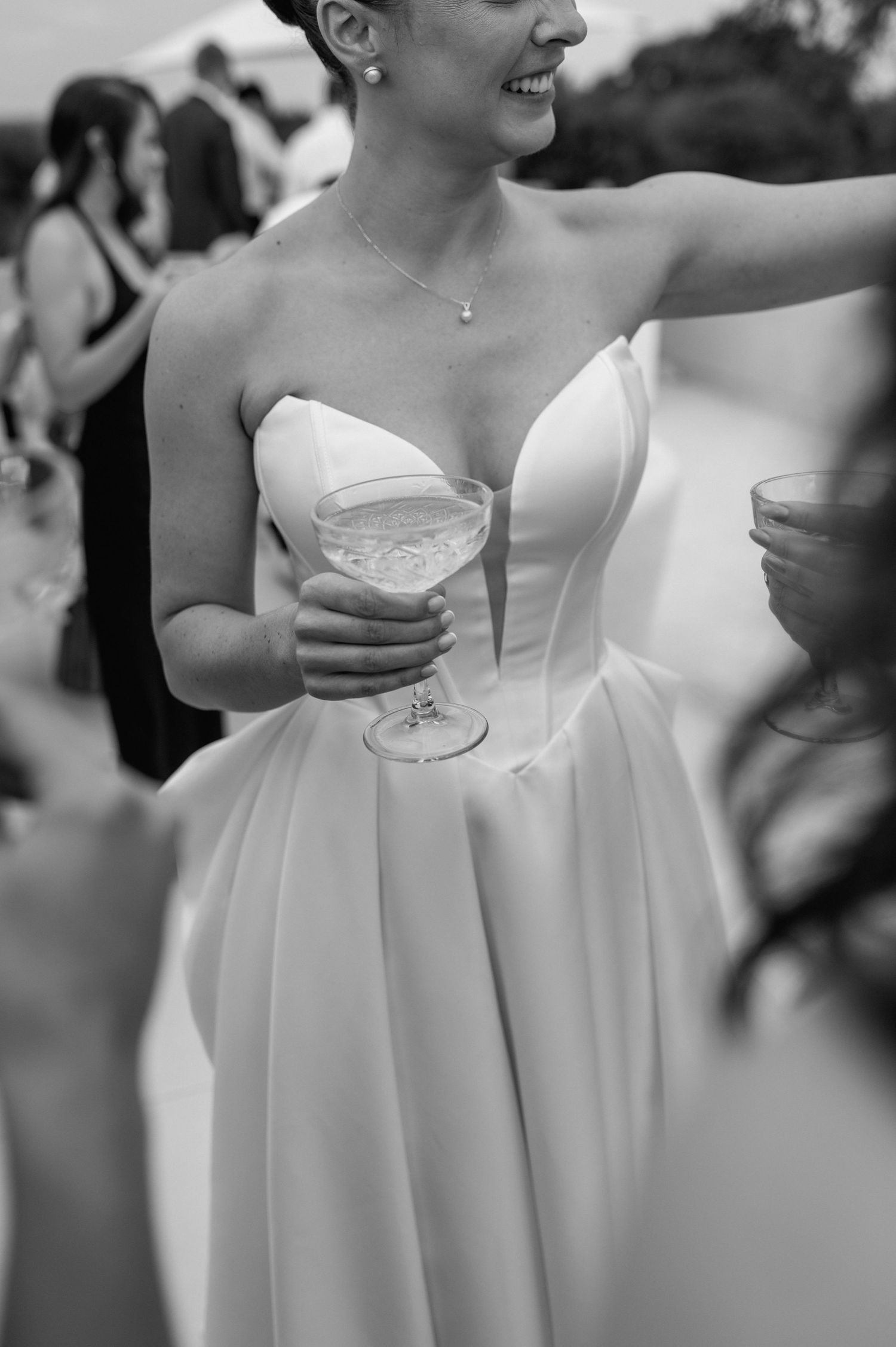 Black and white photo showing bridesmaids in white dresses holding champagne glasses.