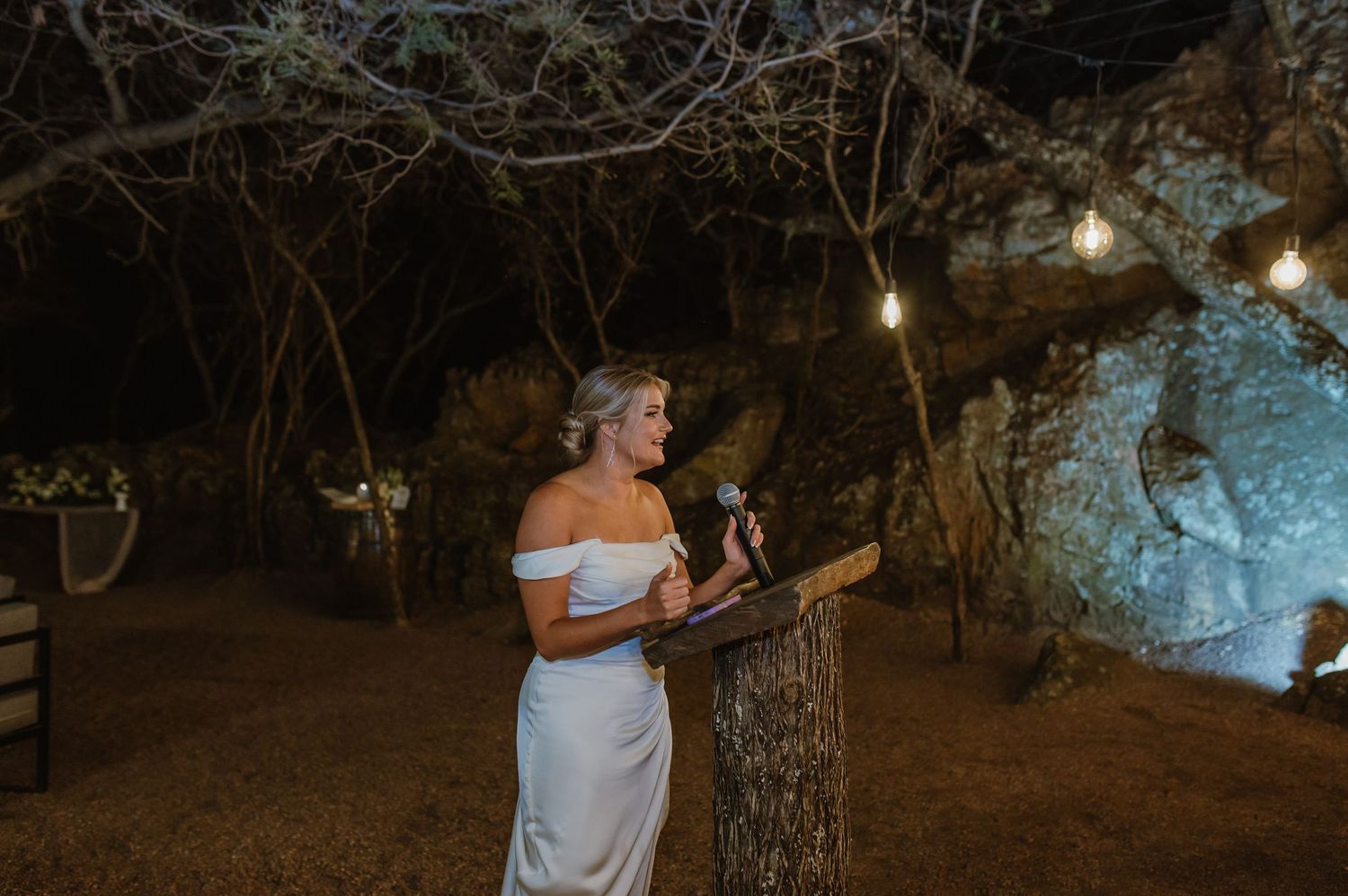 Outdoor wedding reception setup with string lights illuminating the natural surroundings.