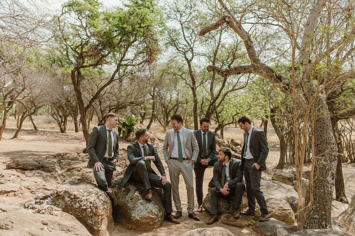 Wedding party members standing in a wooded area with natural rock formations.