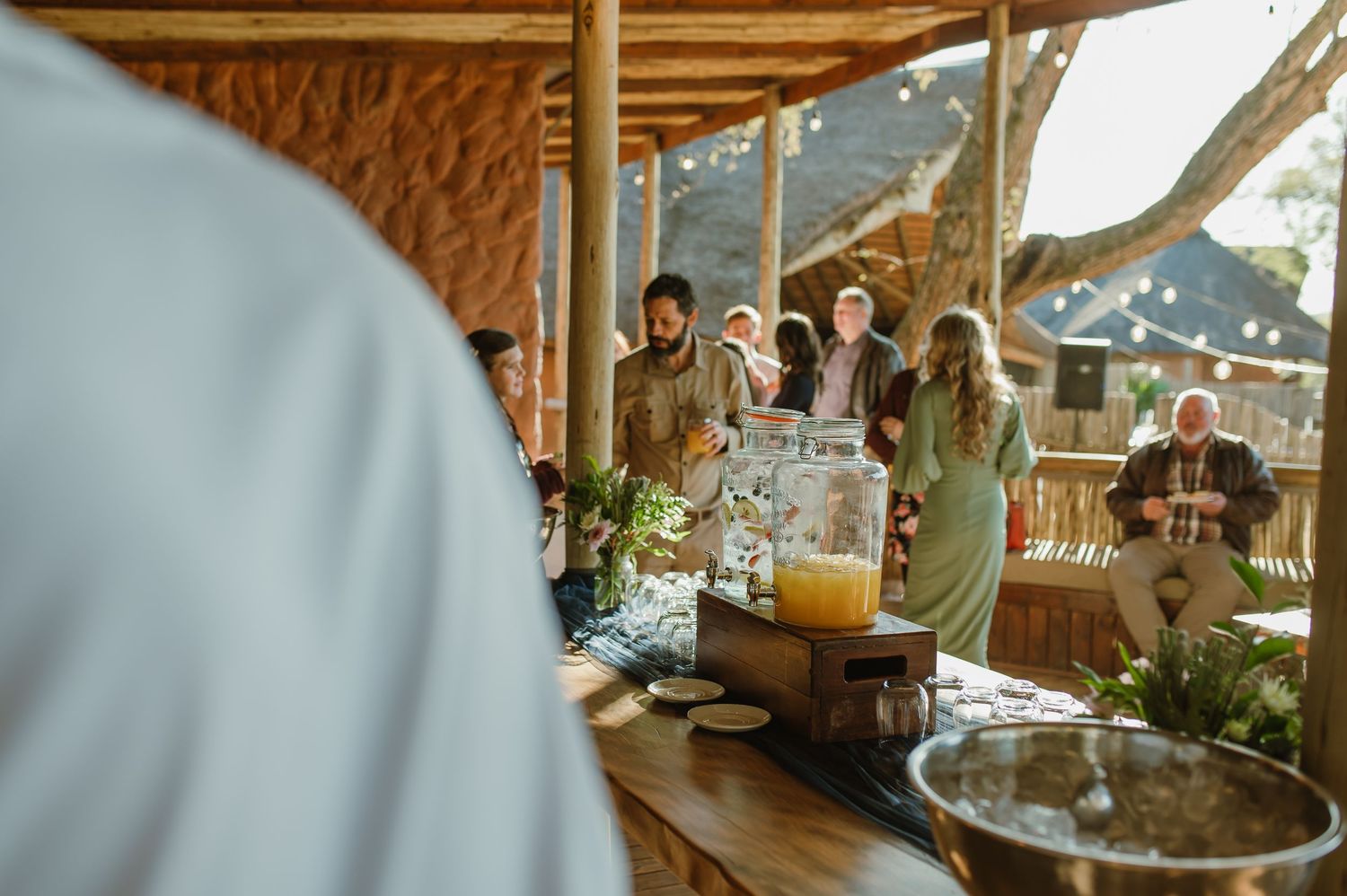 Outdoor wedding reception setup with wooden beams and natural lighting.