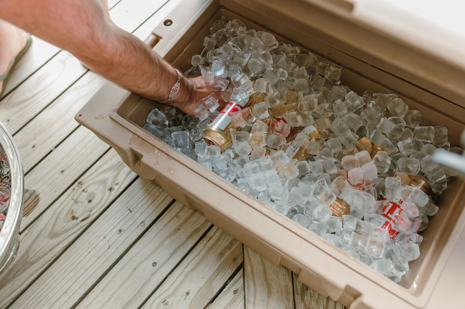 Close-up of hands sorting through crushed ice in a wooden container.