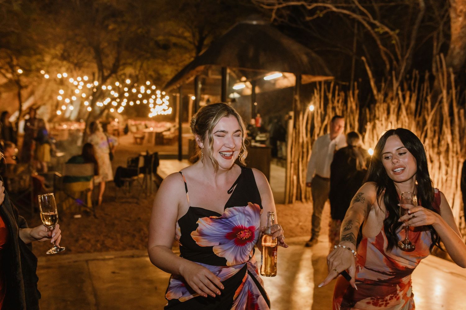Guests celebrating on the dance floor at a rustic outdoor wedding venue with string lights.