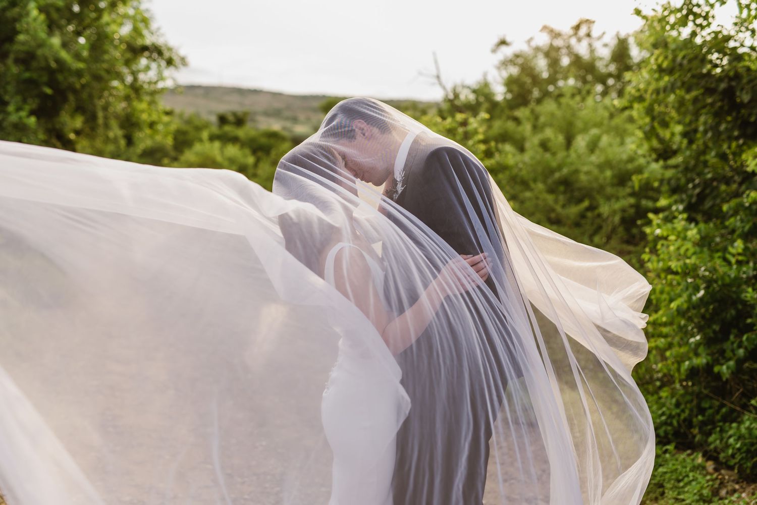 Flowing white veil catches the breeze during an outdoor wedding photoshoot.