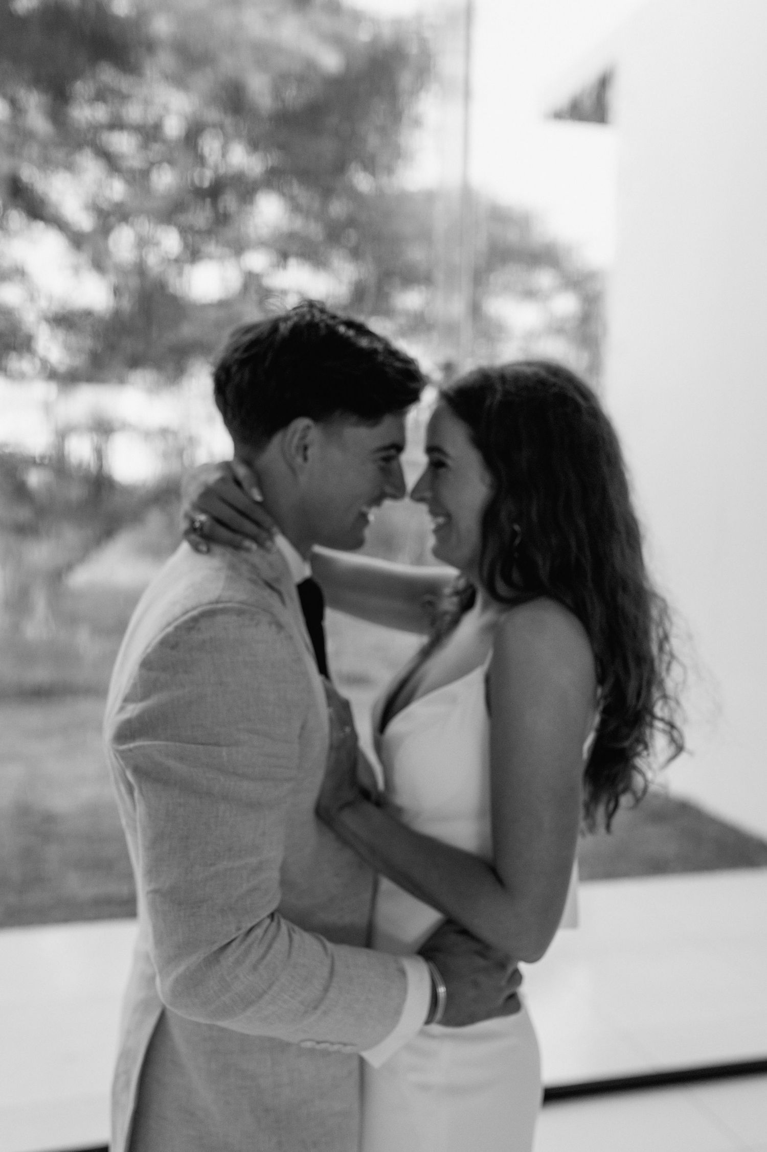 An intimate black and white portrait of a wedding couple sharing a tender moment.