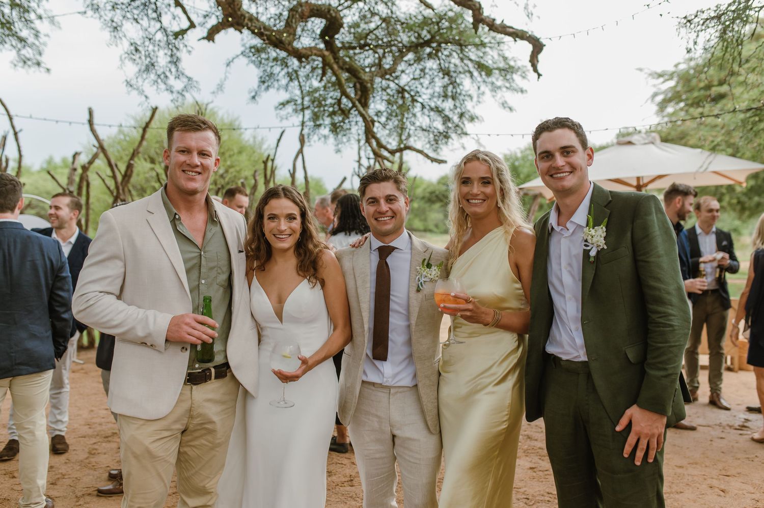 Group photos of wedding guests posing together under trees at an outdoor reception.